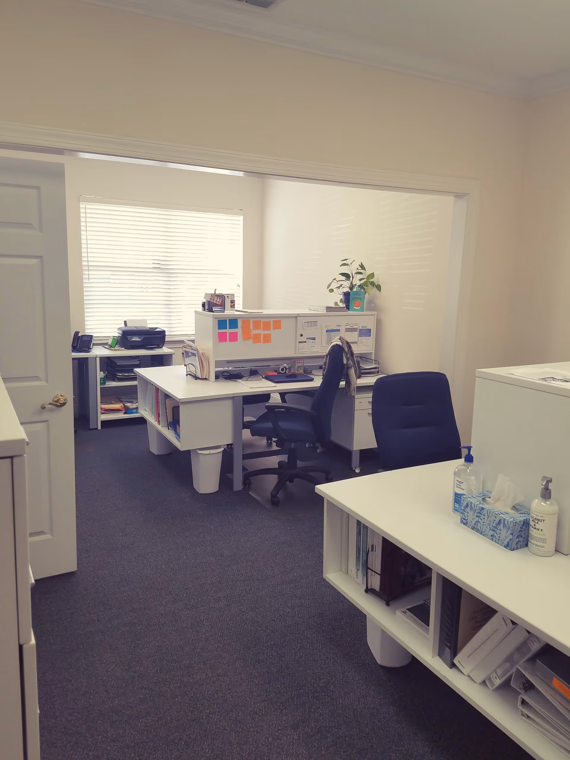 Office workspace with desks, chairs, filing cabinets, and a plant in a Senior Helpers facility.