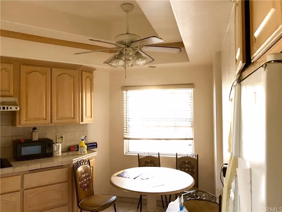 Cozy kitchen and dining area with round table, chairs, and ceiling fan.