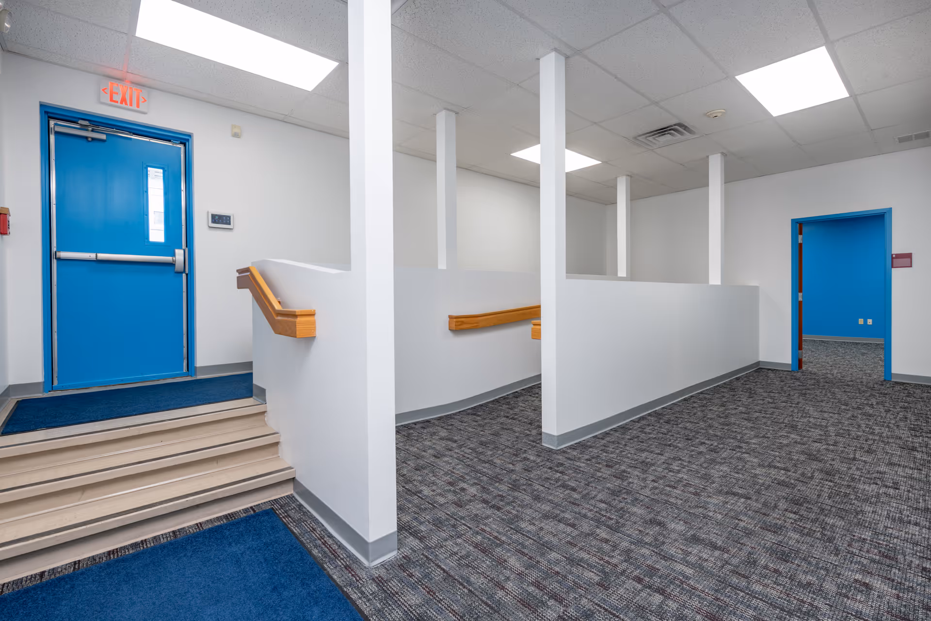 Interior hallway of a senior facility with blue doors, white walls, and carpeted flooring.