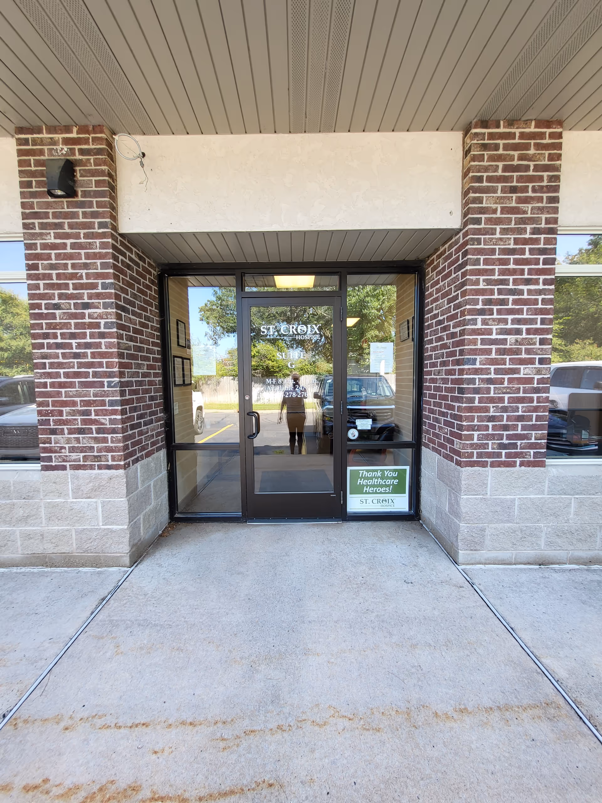 Brick building entrance with glass doors, brick columns, and a reflection of the photographer.
