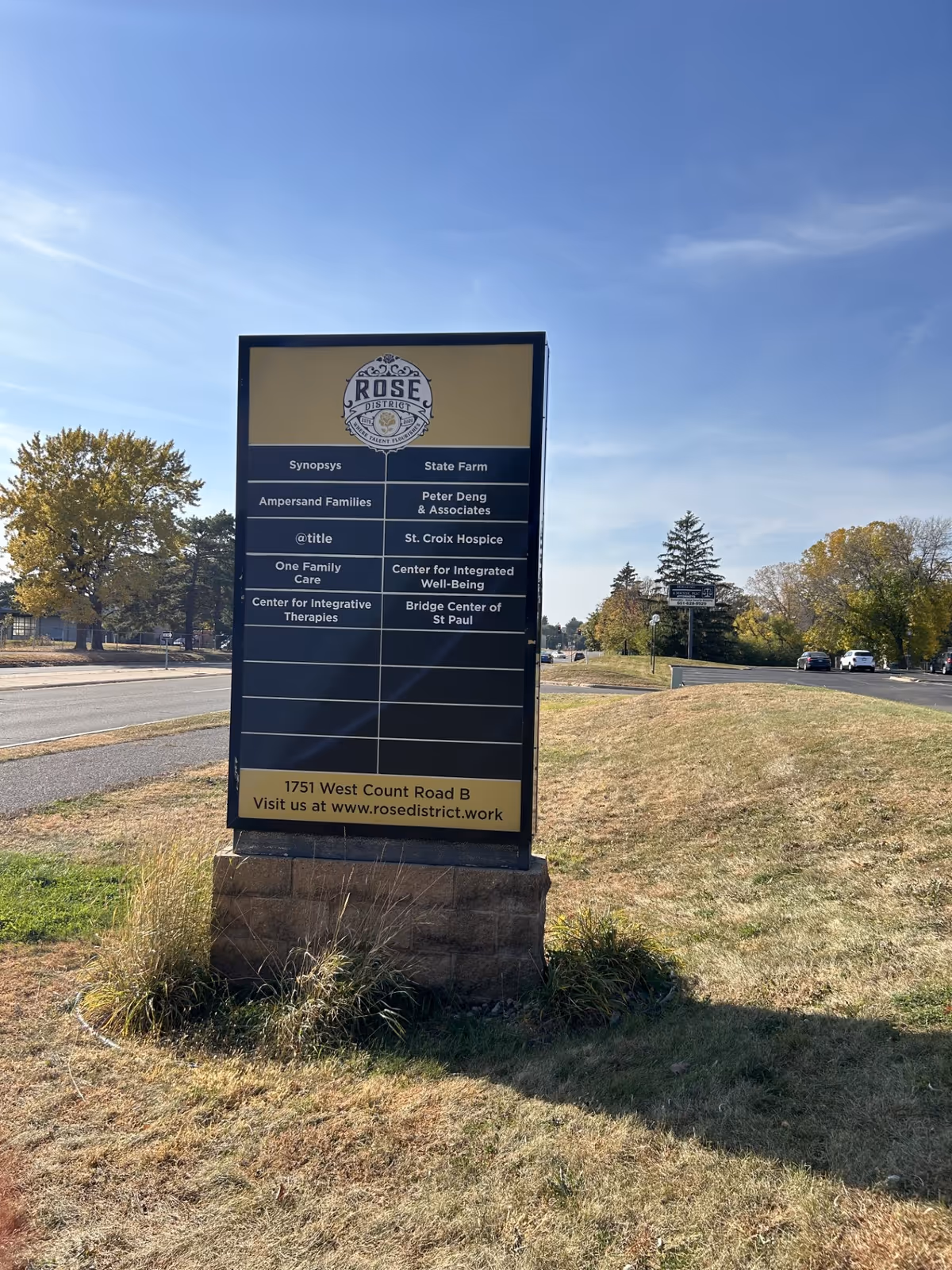 Tall roadside signboard listing tenants, including St. Croix Hospice, on a grassy median.