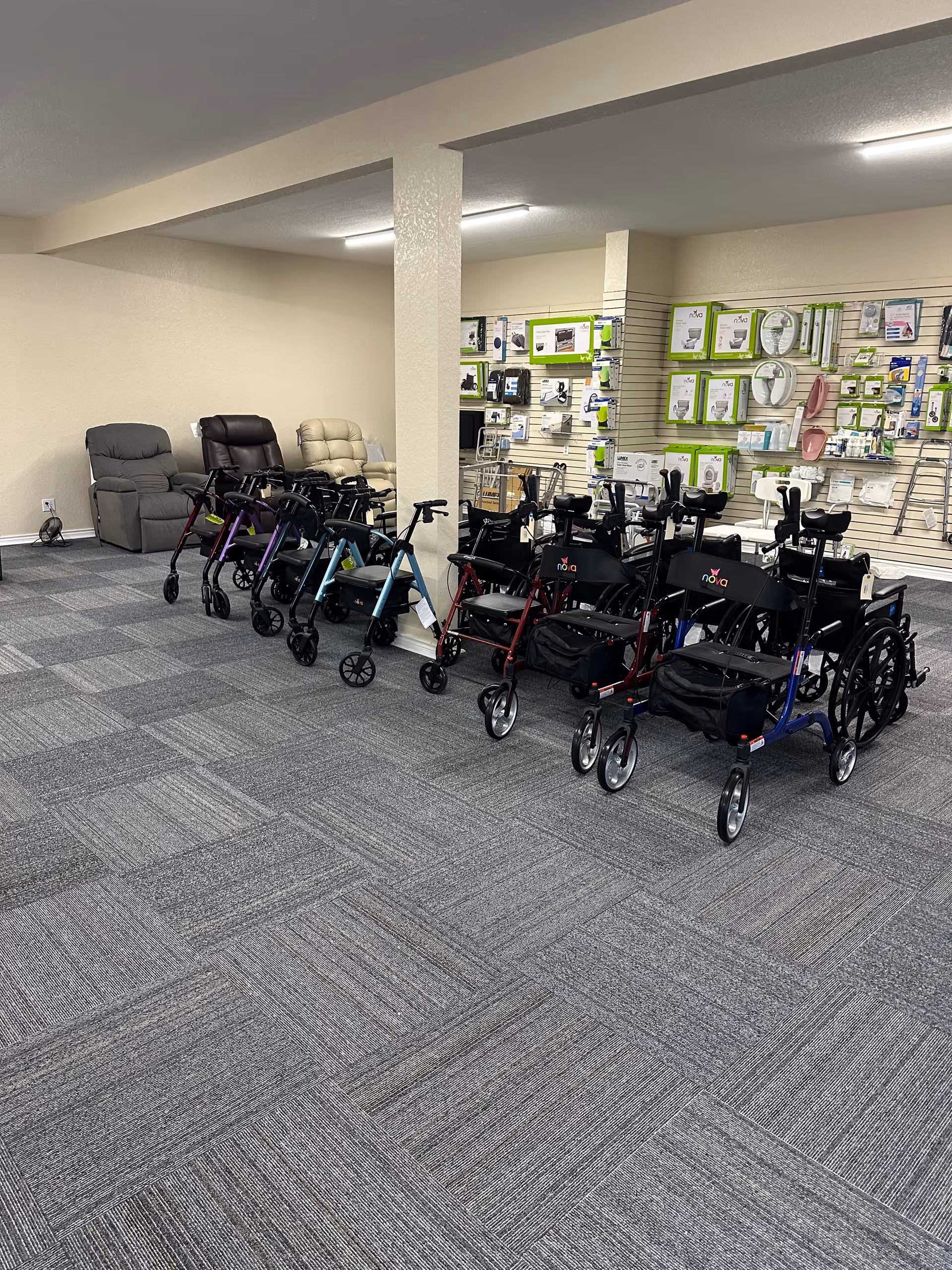 Indoor showroom with wheelchairs and walkers arranged by a wall.