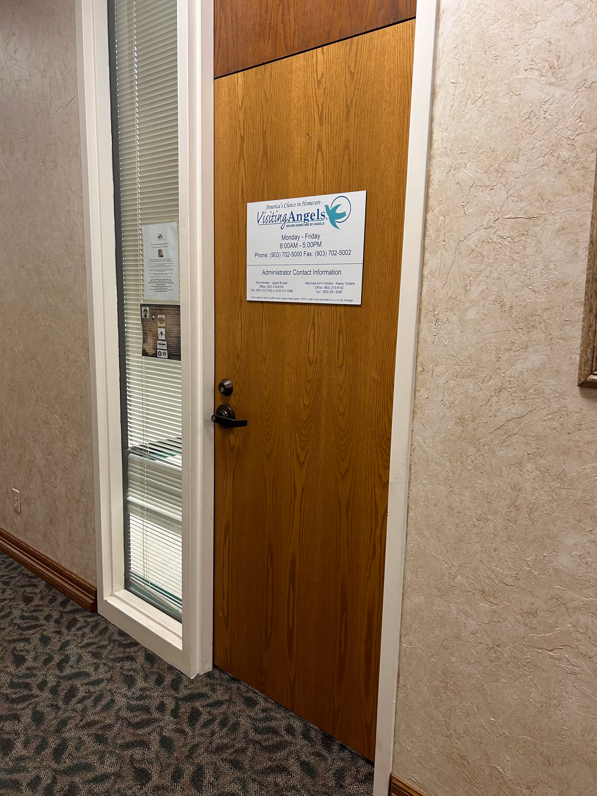 Wooden door with Visiting Angels sign in a hallway of a senior care facility.
