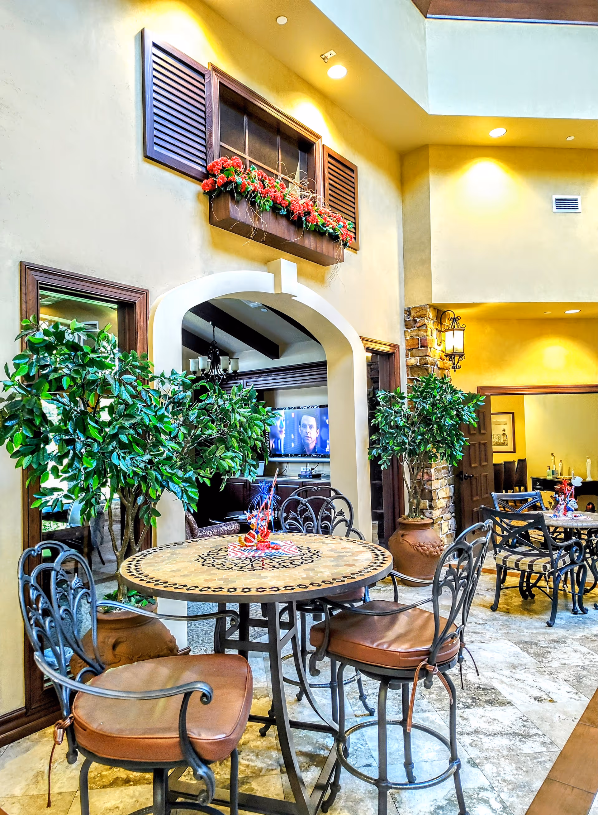 Indoor lounge area of Gulfside Healthcare Services with round table, chairs, plants, and TV.