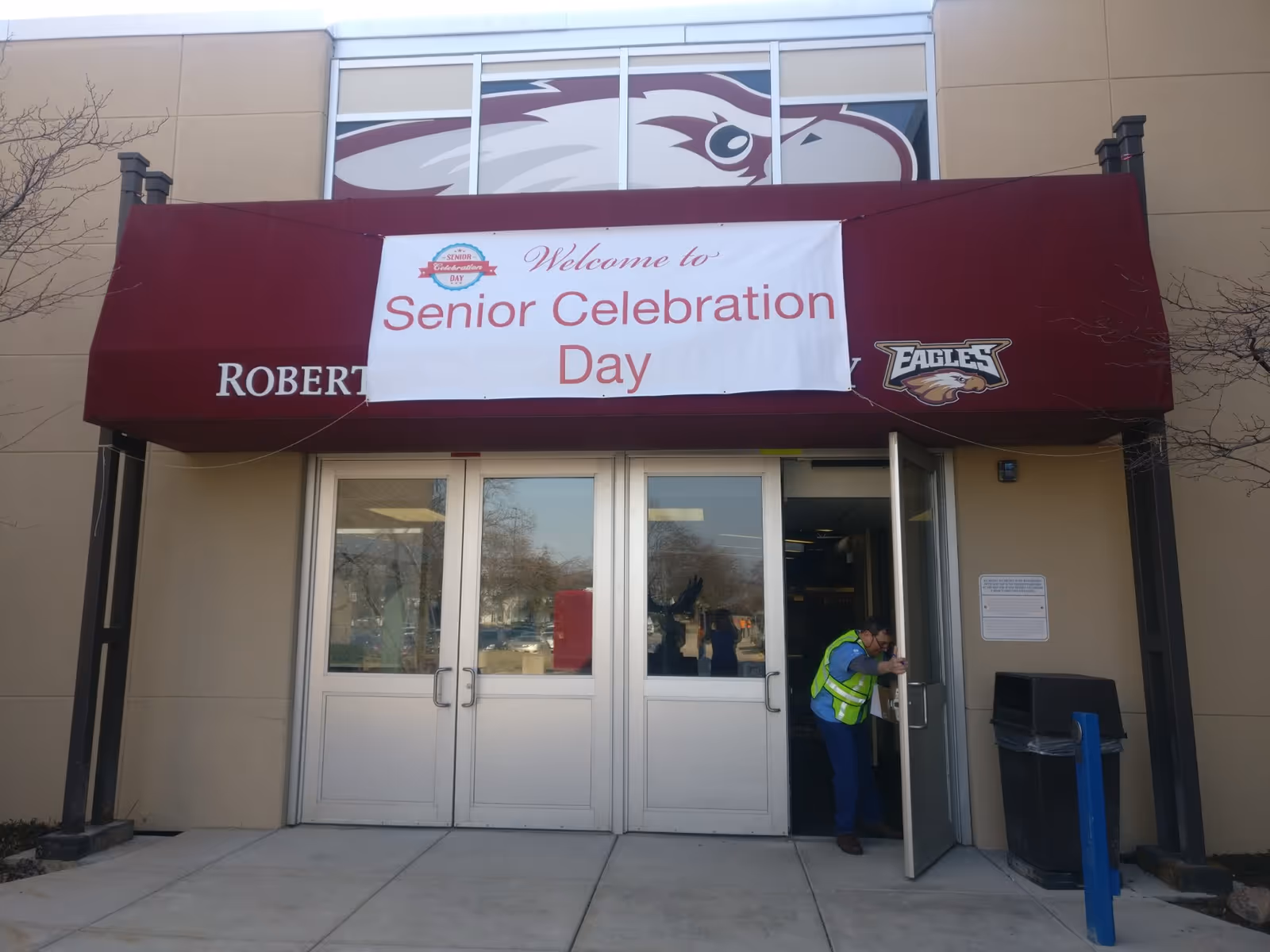 Front entrance of a building with maroon canopy banner reading Senior Celebration Day.