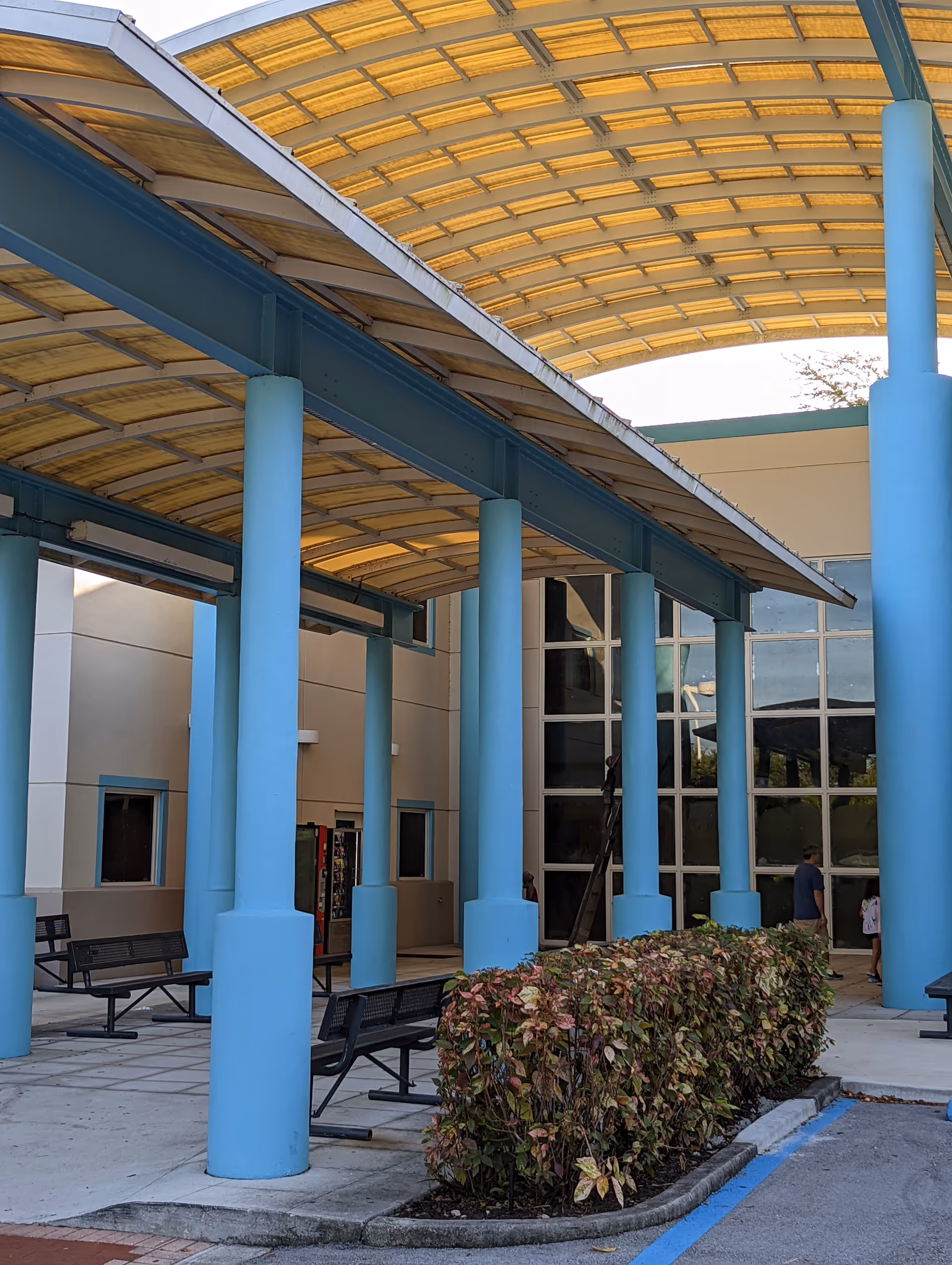 Exterior view of Nicklaus Children's Dan Marino Outpatient Center entrance with blue pillars and benches.