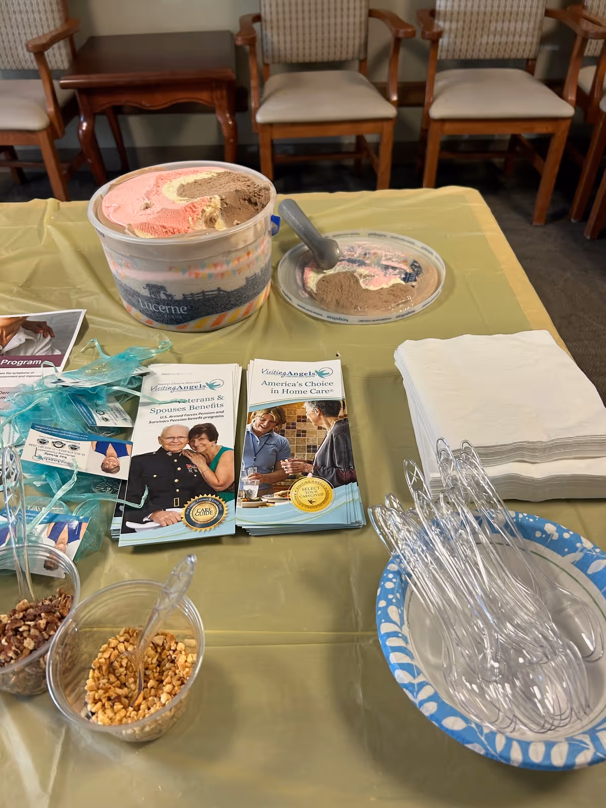Table setup with ice cream tubs, spoons, napkins, and brochures in an indoor room.