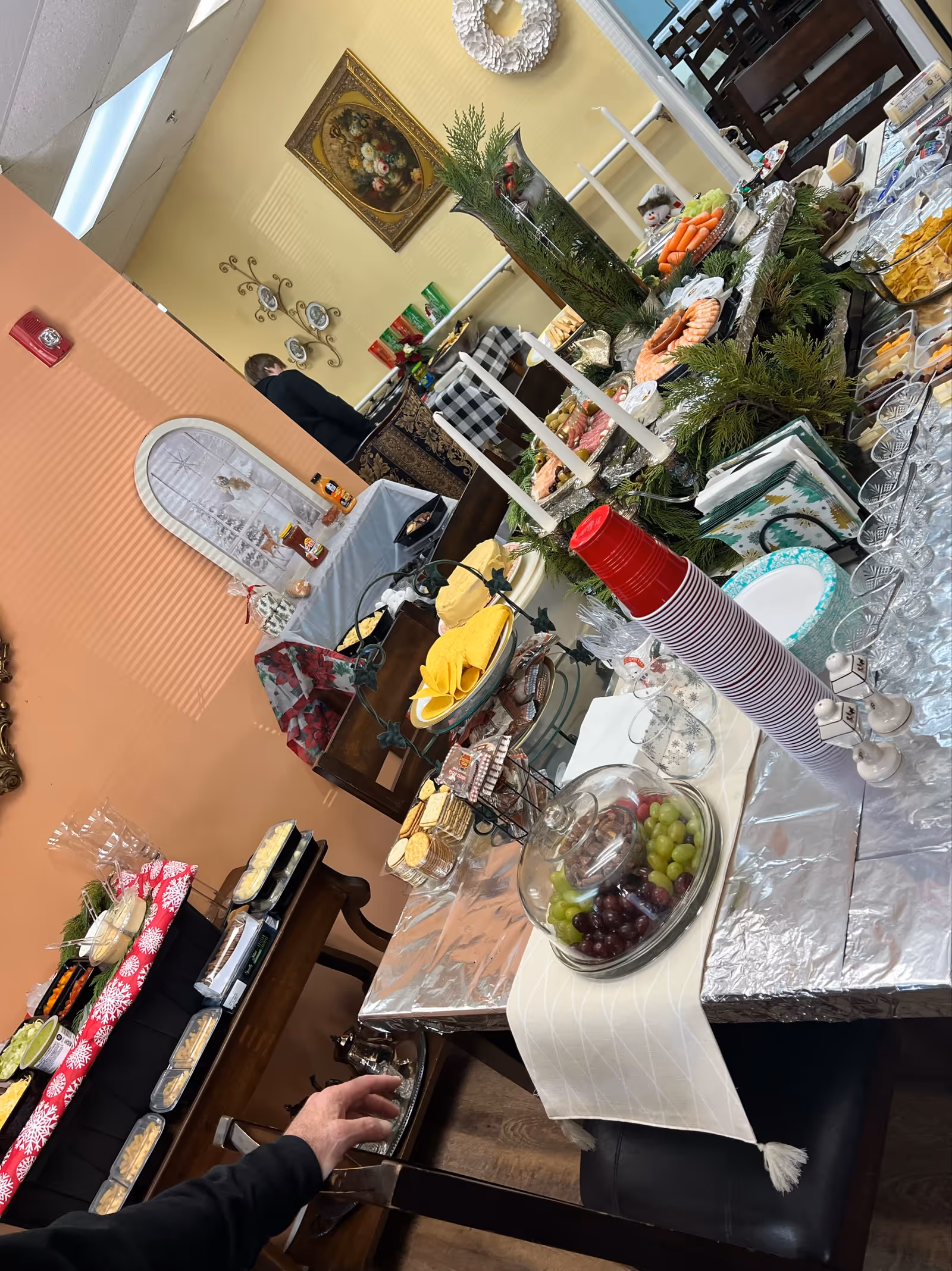 Buffet-style dining table with fruits, dishes, cups, and decorations in a senior living facility.