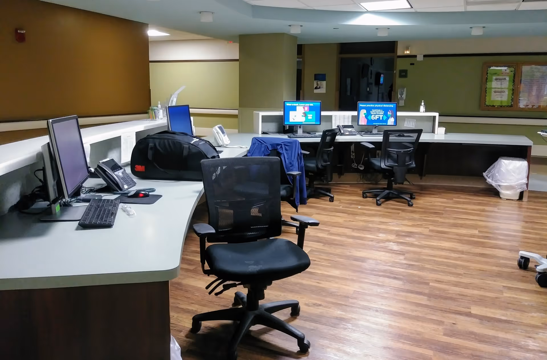 Curved front desk with computer monitors and chairs in a hospital reception area.