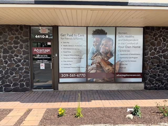 Exterior storefront of Advantage Home Care with large window posters and stone facade.