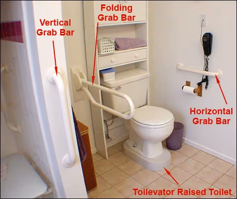 Accessible bathroom with toilet, folding and fixed grab bars, and safety rails.