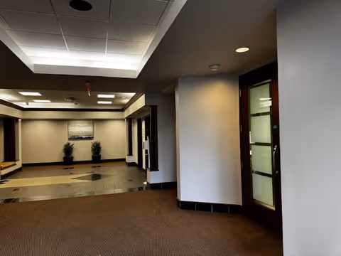 Interior lobby area with tiled floor, potted plants, and frosted glass doors