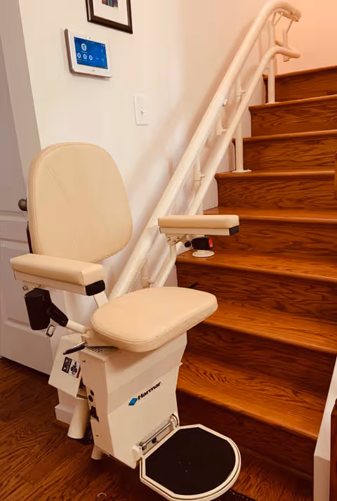Interior stairwell with a beige stairlift installed beside wooden stairs.