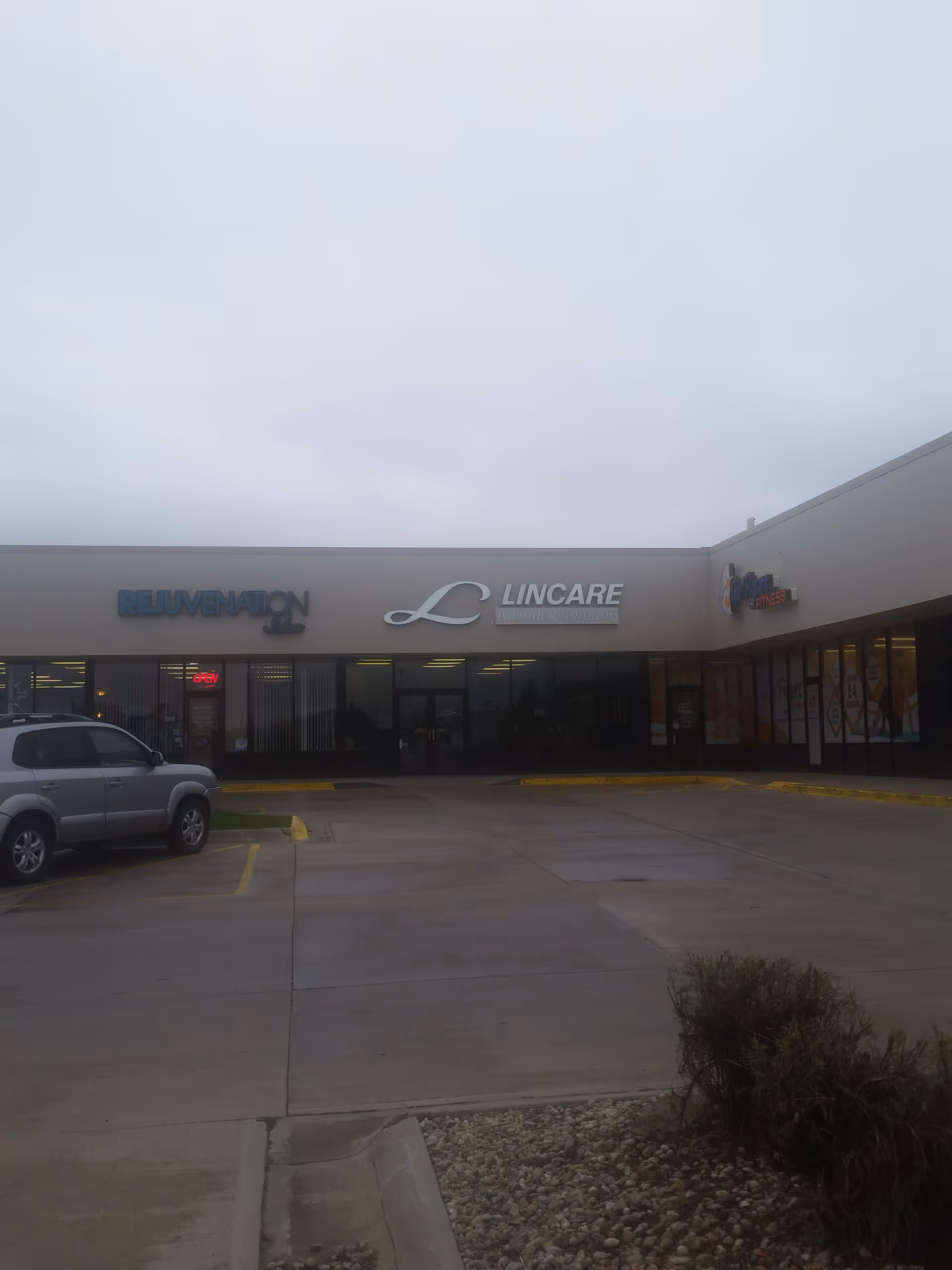 Exterior view of a LinCare storefront in a strip mall with a parked SUV.