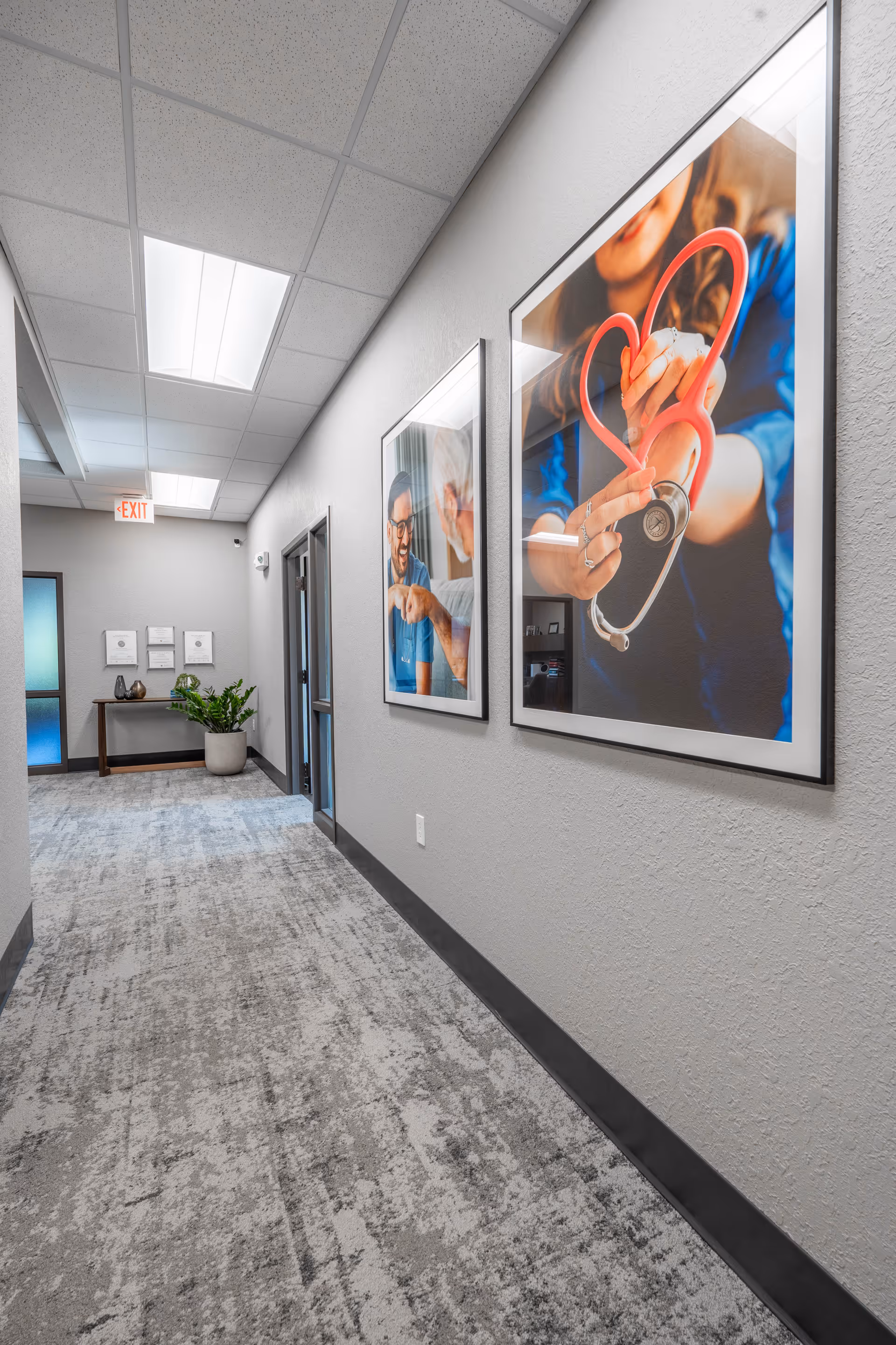 Interior hallway of Haven Home Health and Hospice with framed medical posters and a potted plant.
