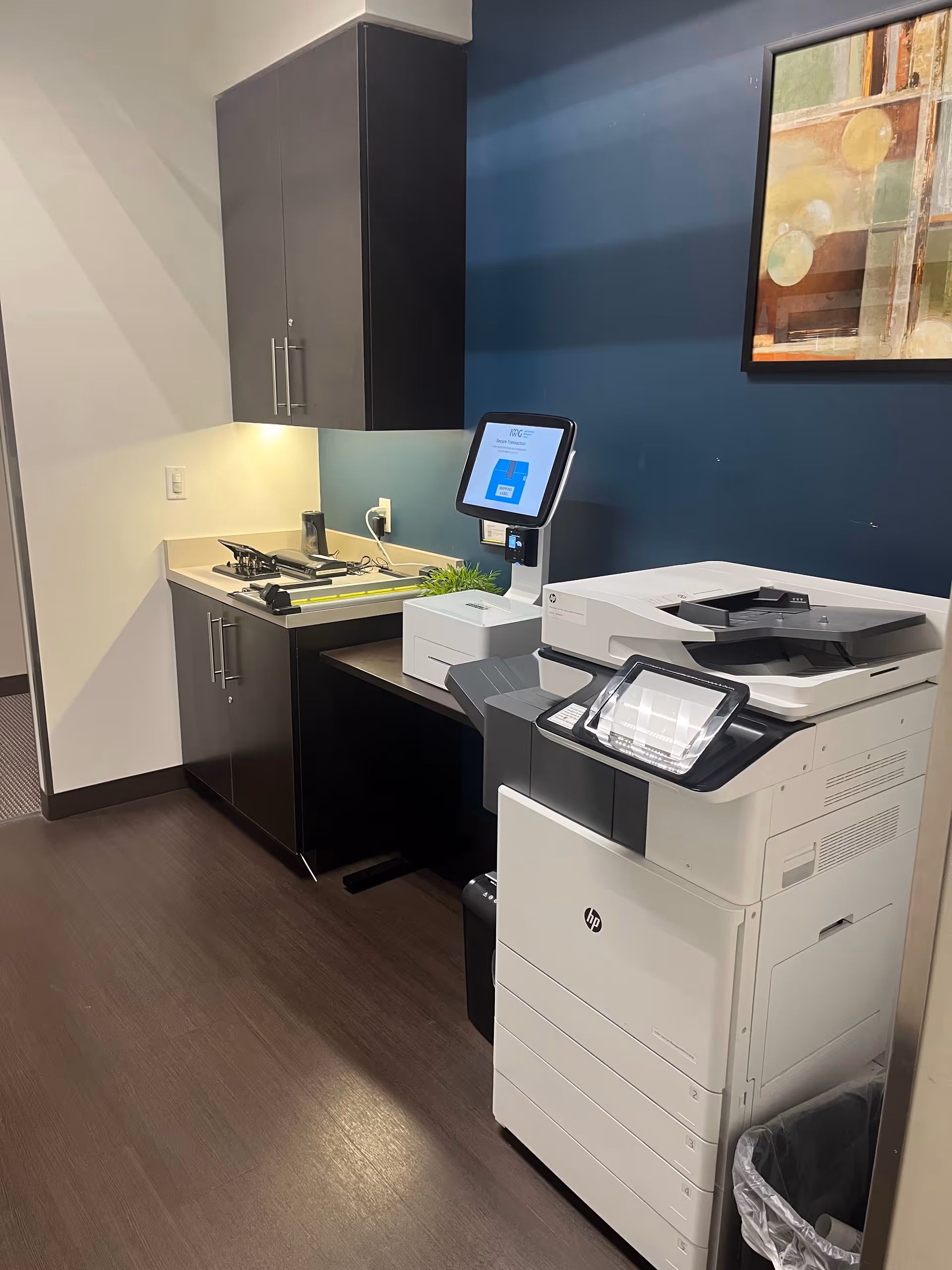 Modern kitchenette with cabinets, stove, and a copier in a staff area.