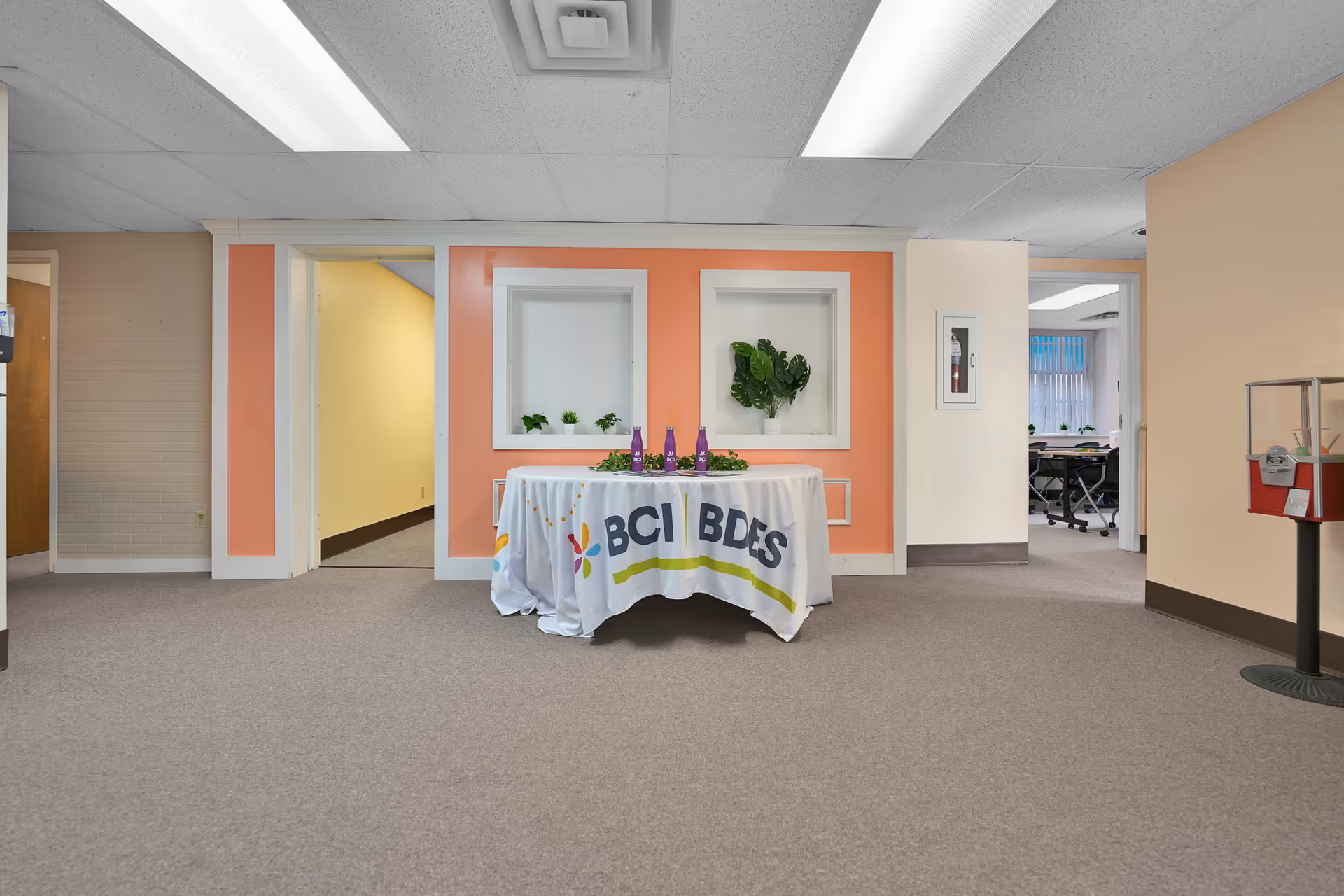 Lobby area with orange accent wall and a round table draped with a BCI tablecloth.