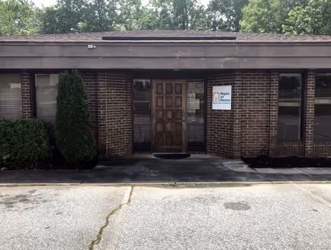 Brick senior living facility entrance with a wooden door and 'Right at Home' sign.