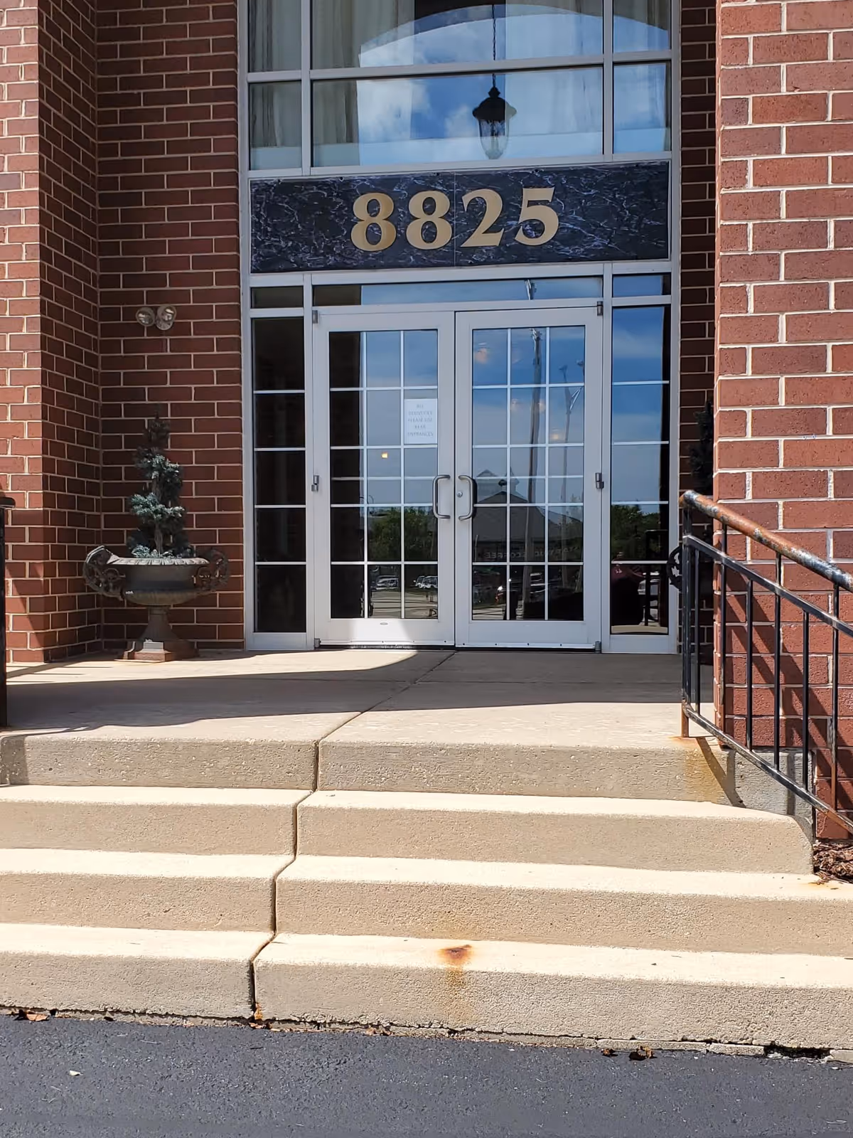 Front entrance of a brick building with glass doors and the number 8825 above
