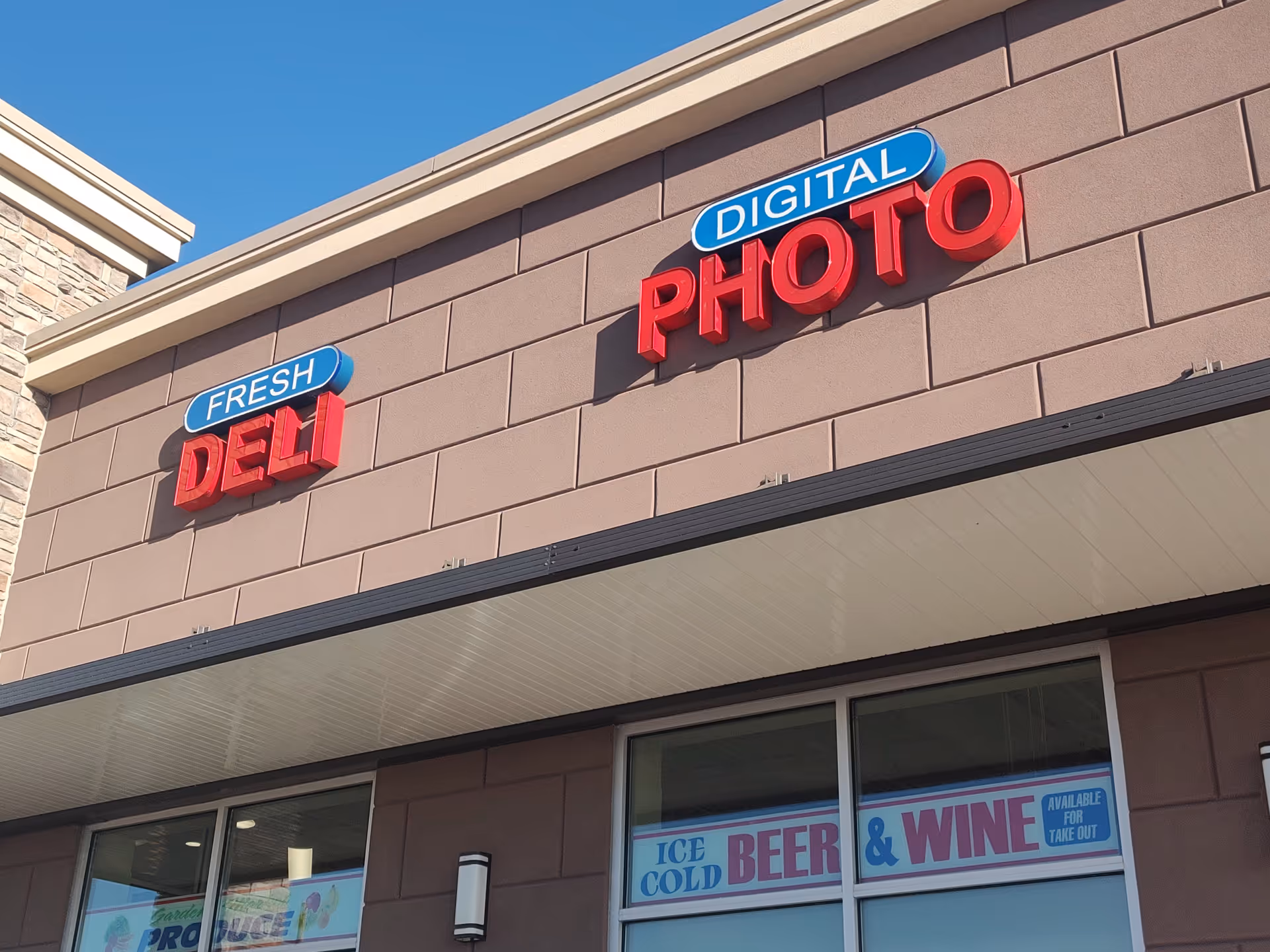 Exterior storefront with signs reading Fresh Deli and Digital Photo on brown brick
