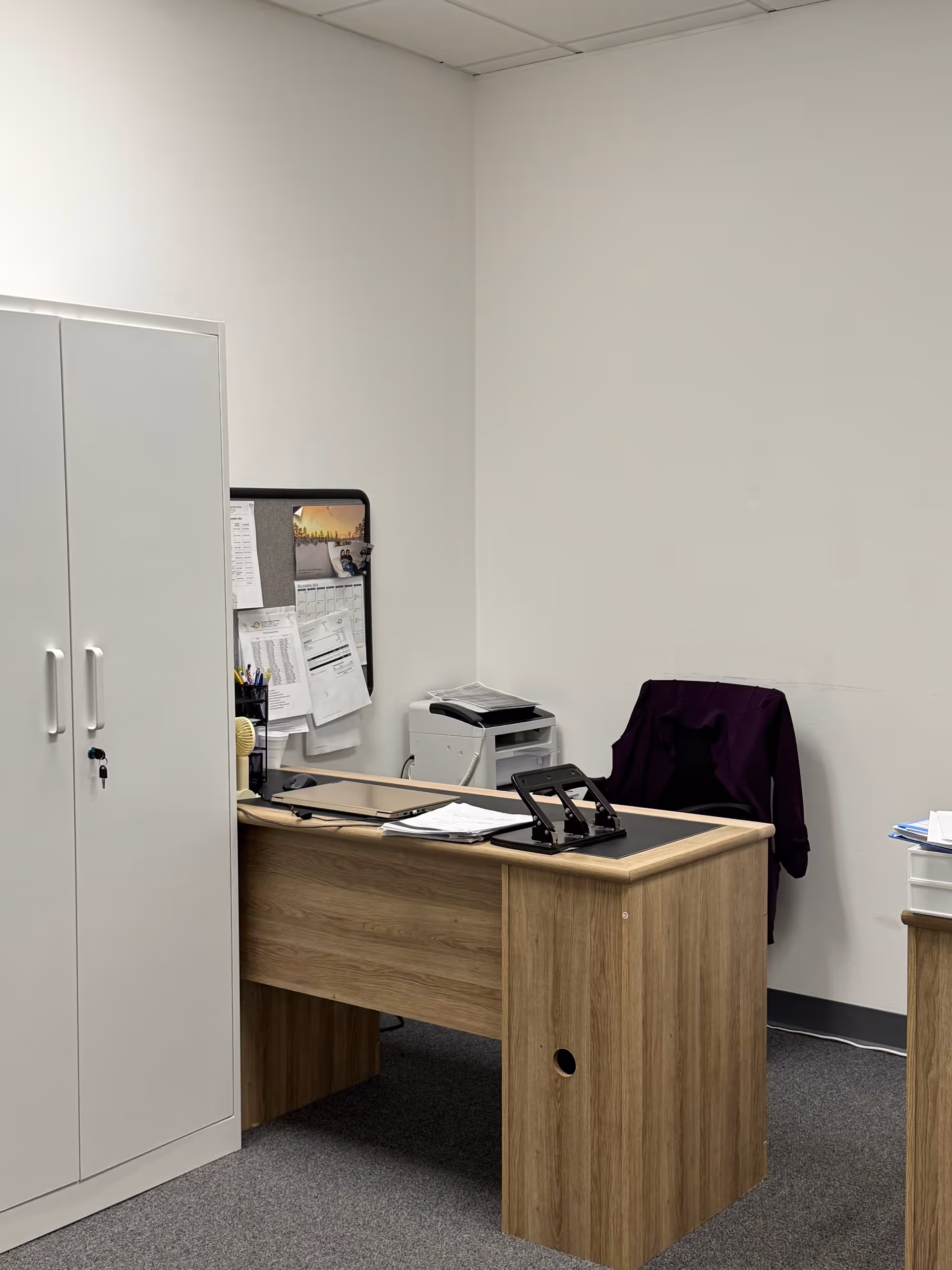 Office desk with papers, printer, and a cabinet in a clean administration room.