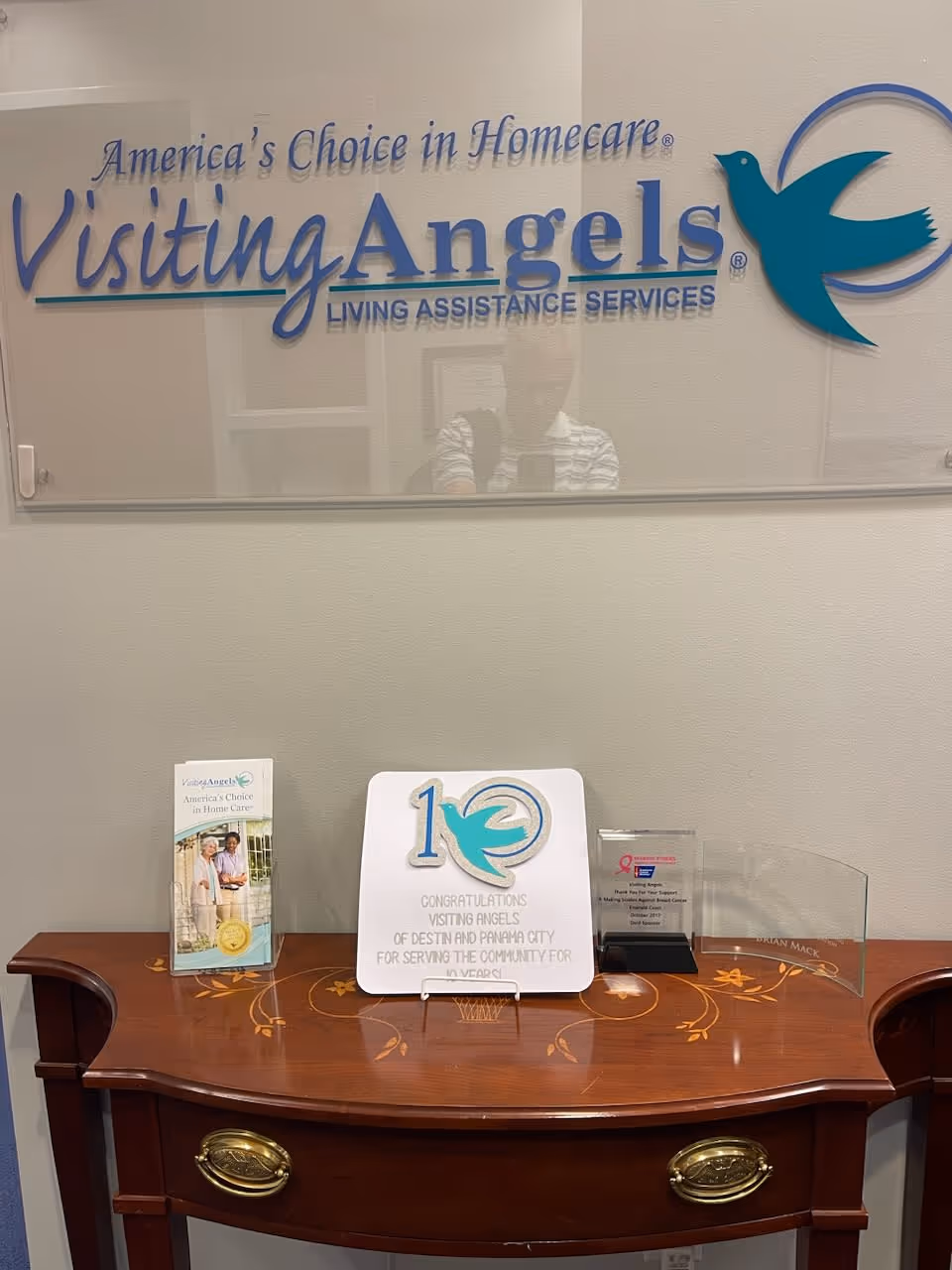 Reception area with a large Visiting Angels sign and a wooden curved desk.
