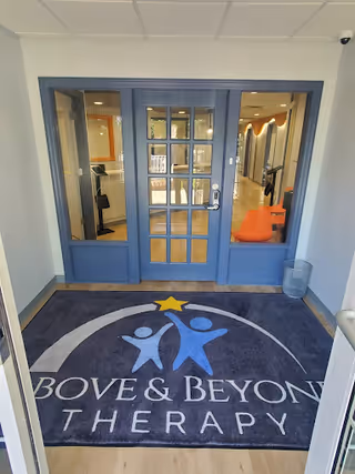 Blue double-door entrance opens to a hallway with orange chairs and a branded mat.