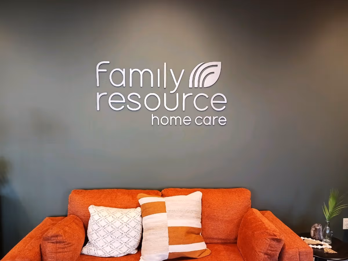 Orange sofa with pillows sits against a blue wall featuring the Family Resource Home Care logo.