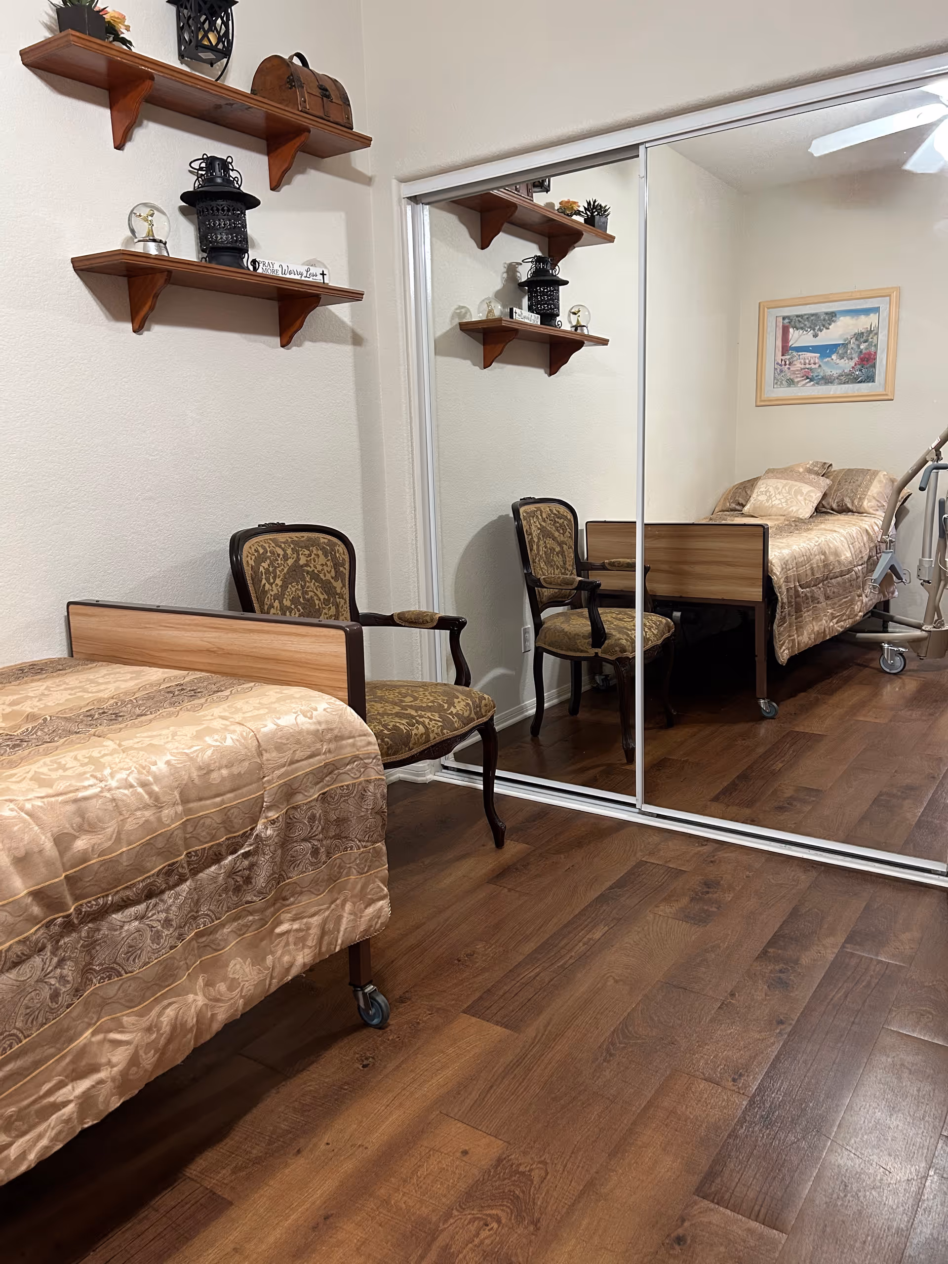 Bedroom in a senior living facility with two beds, chairs, and mirrored closet.