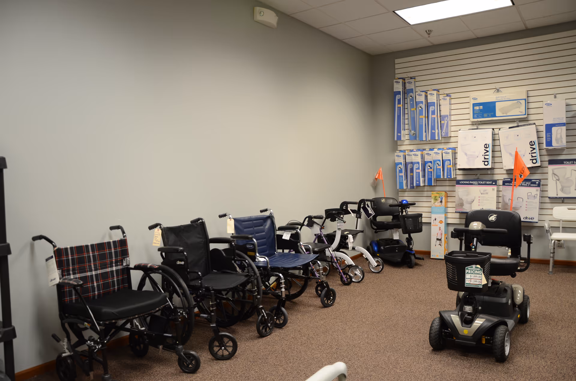Interior showroom with wheelchairs, walkers, and mobility scooters; boxed supplies on shelves.