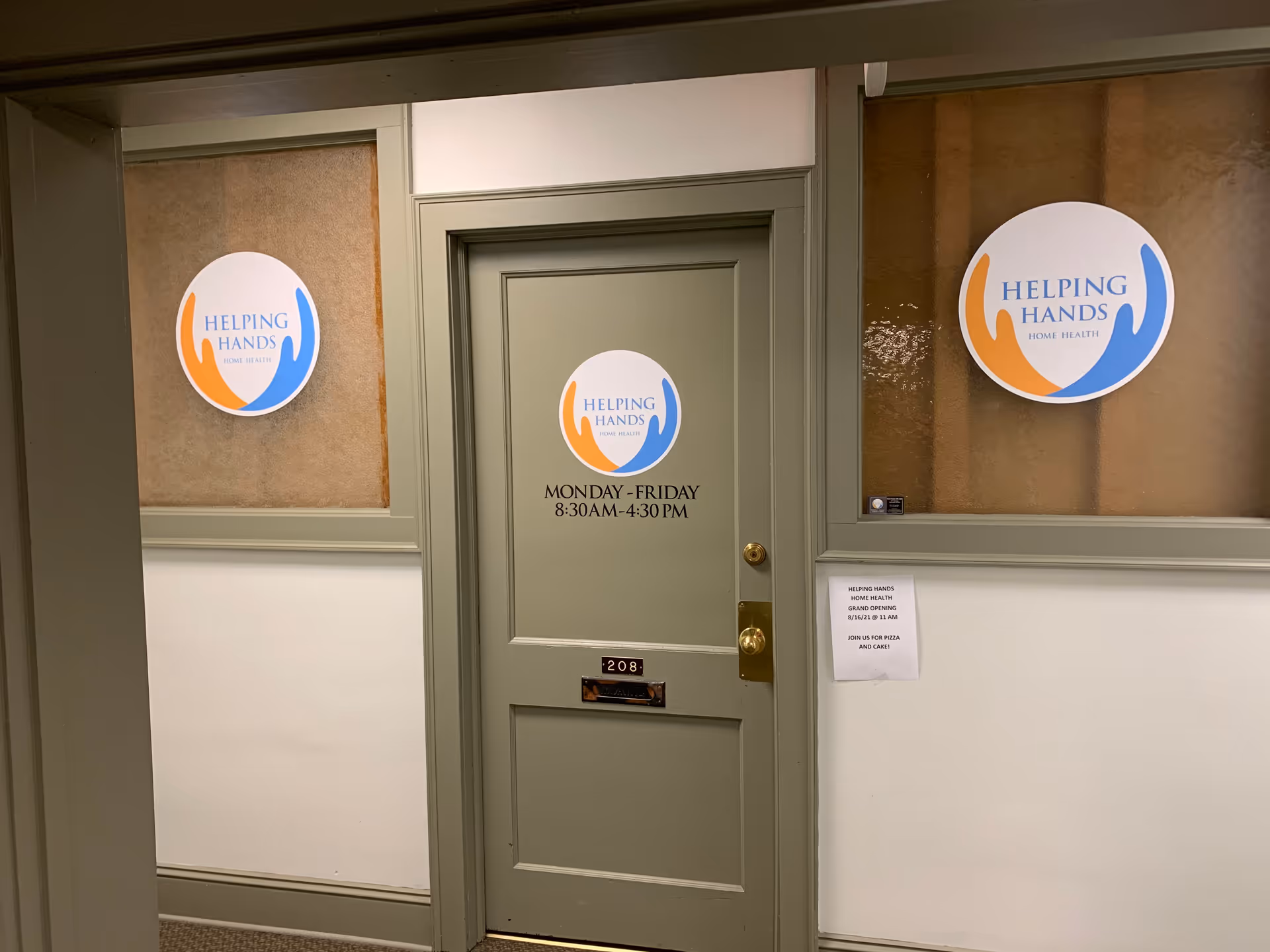 Interior hallway with a green door and circular Helping Hands Home Health logos on window panels.