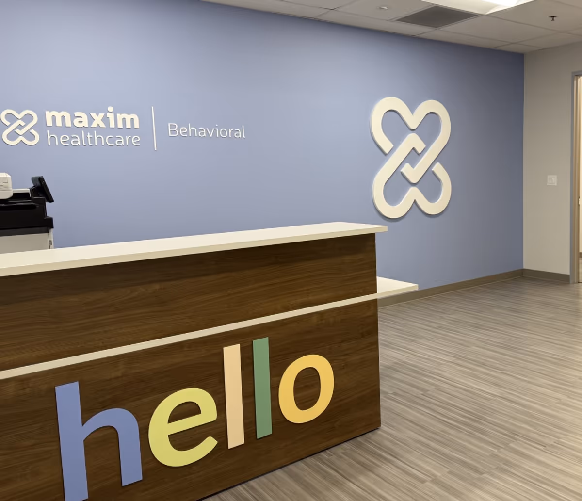 Reception desk in a blue-walled lobby with a large colorful 'hello' on the front.