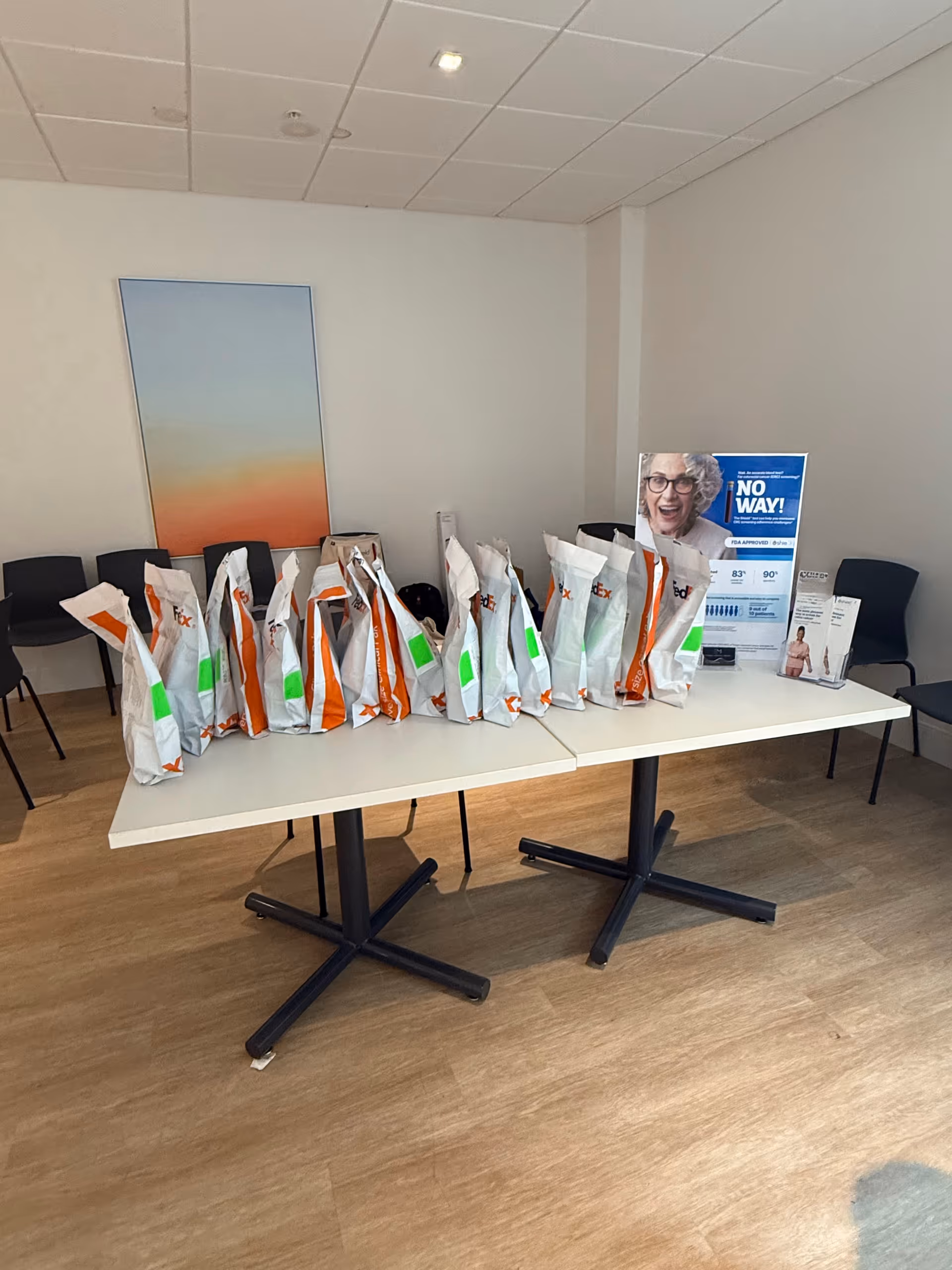 A conference room with a long table filled with white and orange gift bags.
