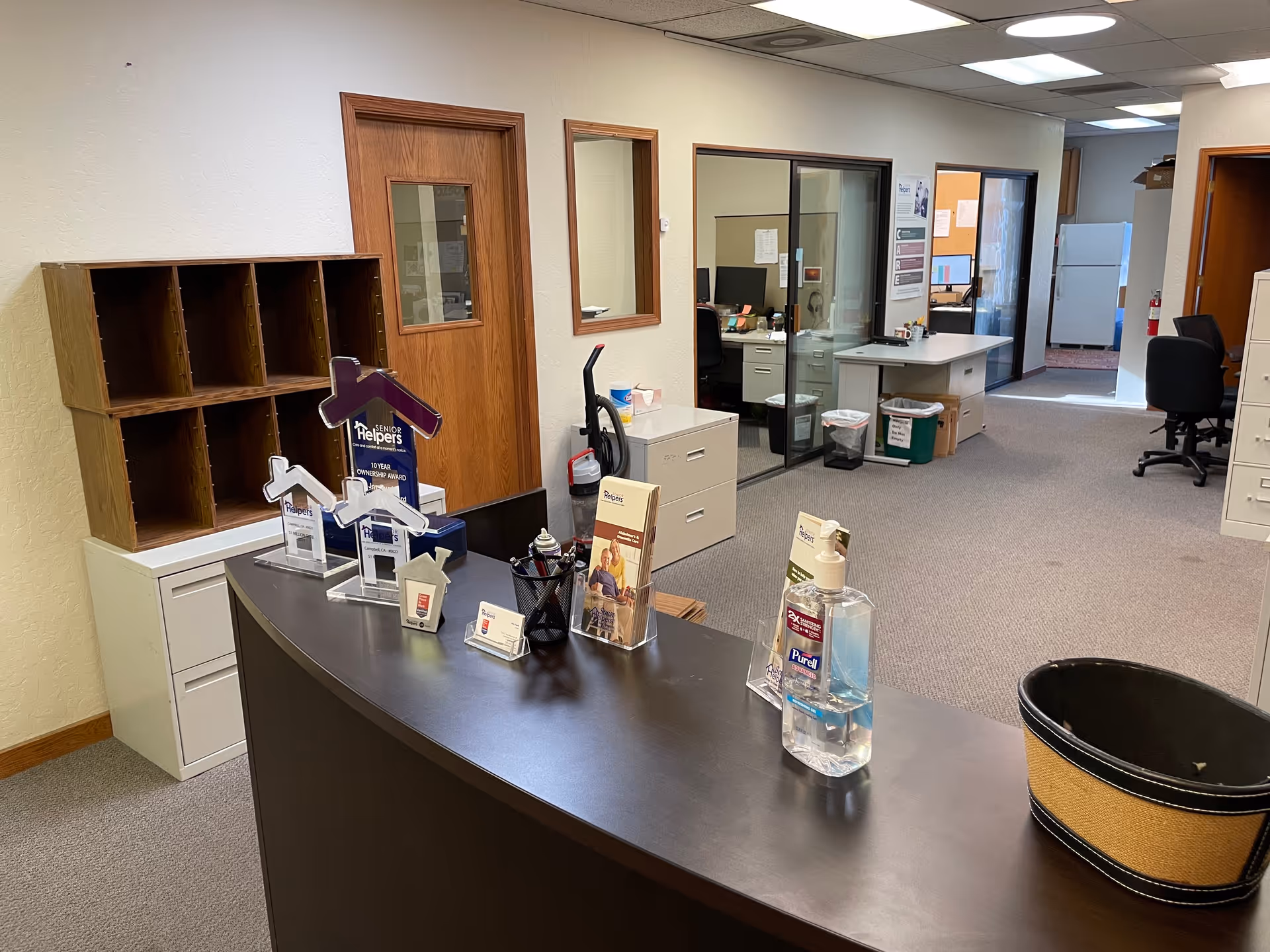 Reception desk in a Senior Helpers facility with cubby shelves and office area.