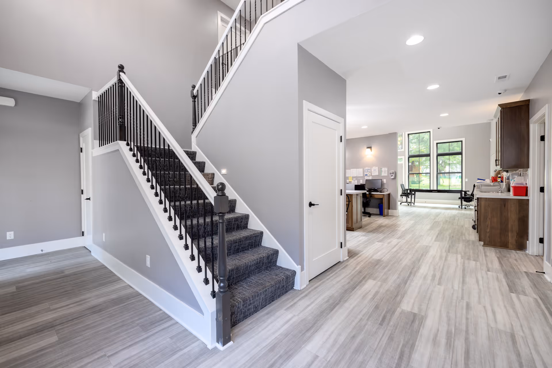 Open interior with staircase, hallway, desk, and kitchenette in a modern senior living space.