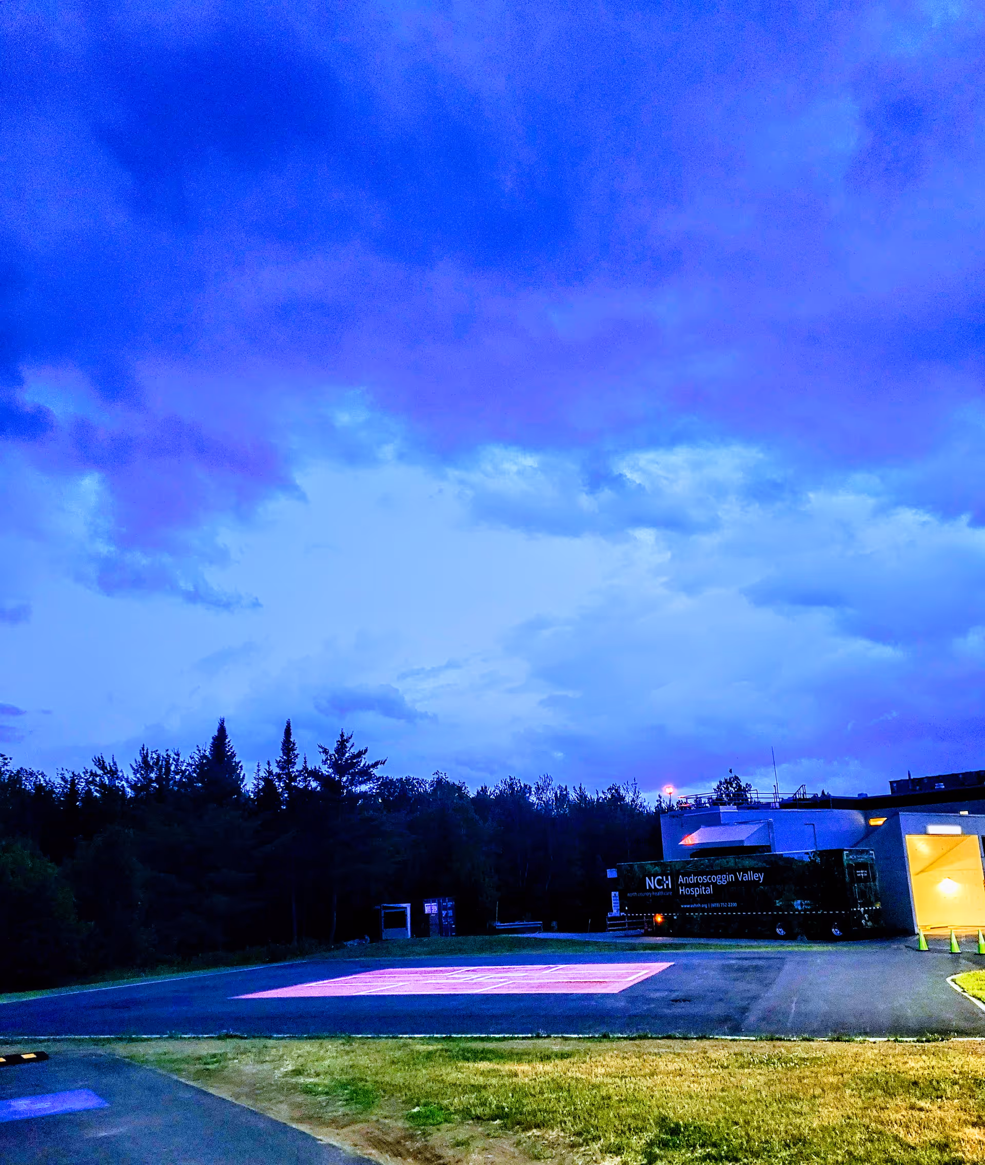 Outdoor view of Androscoggin Valley Hospital exterior with a parked service bus and illuminated entrance.