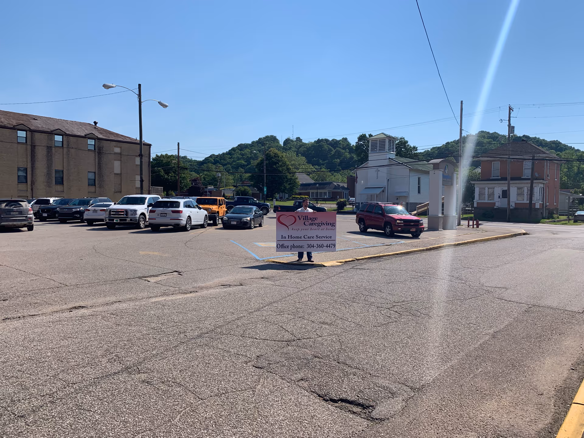 Parking lot in front of a building with a Village Caregiving sign and parked cars.