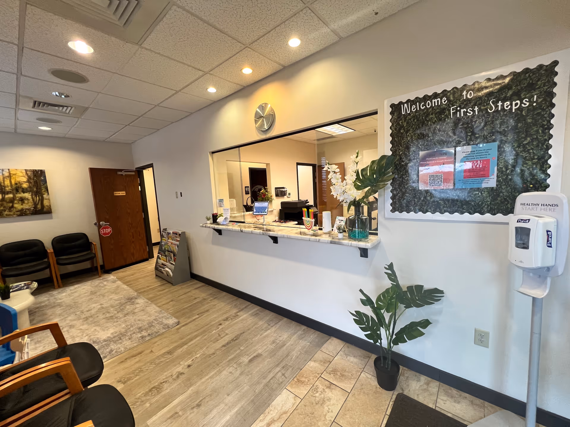 Reception area with a front desk, seating, plants, and a welcome sign.