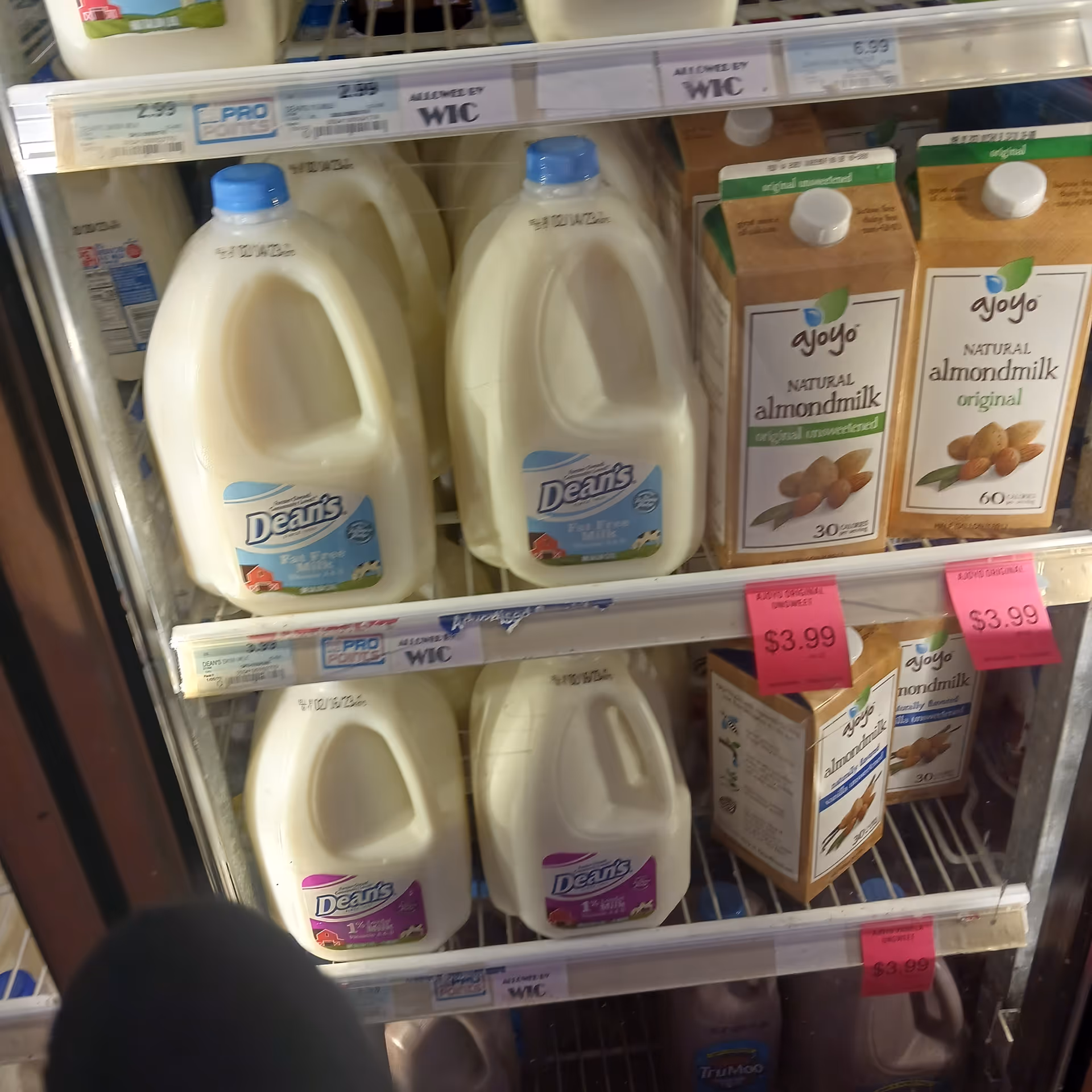 Store shelf with gallons of milk and almond milk cartons at Discount Drug Mart