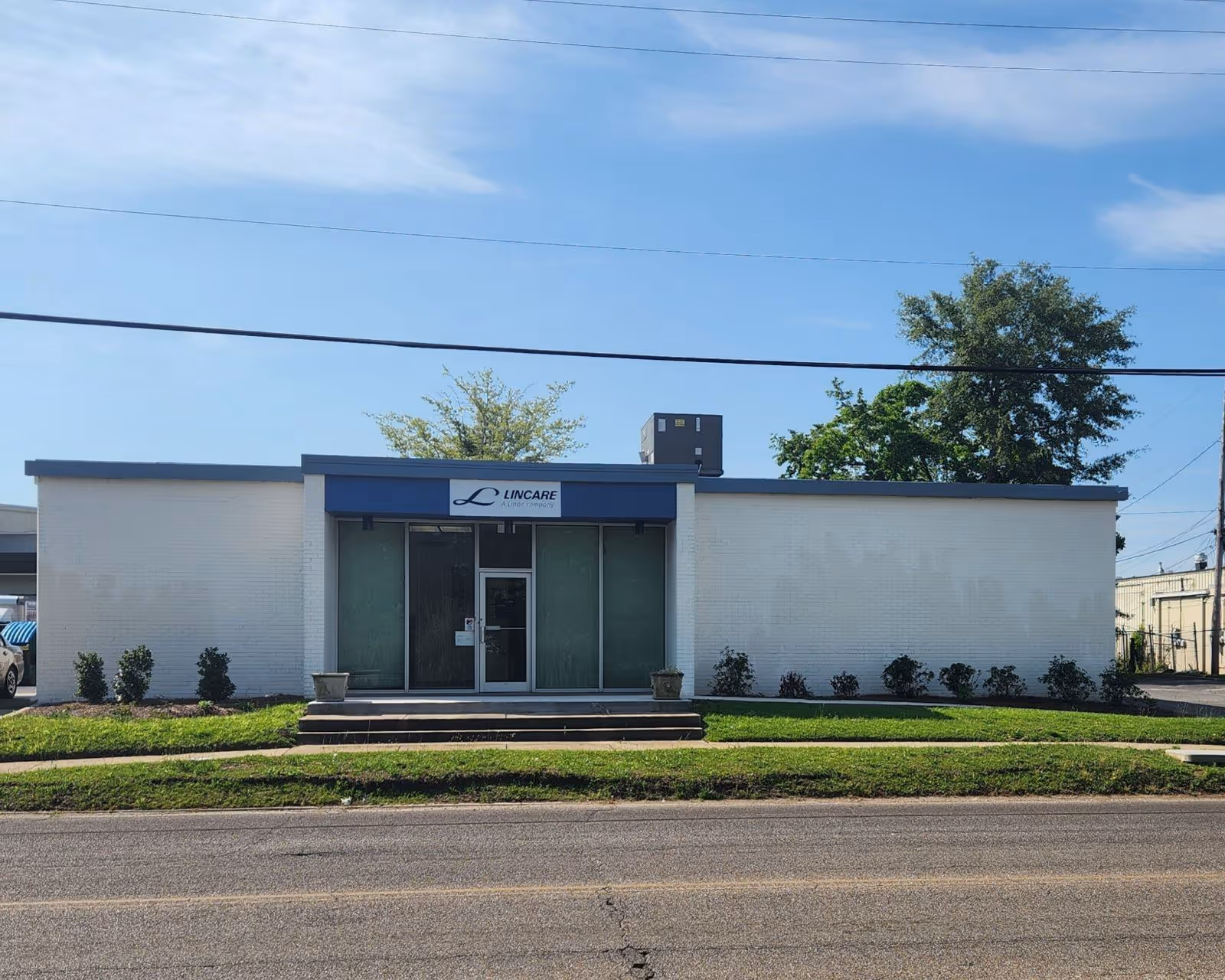 A single-story white building with blue trim and a glass entry door labeled LINCARE.