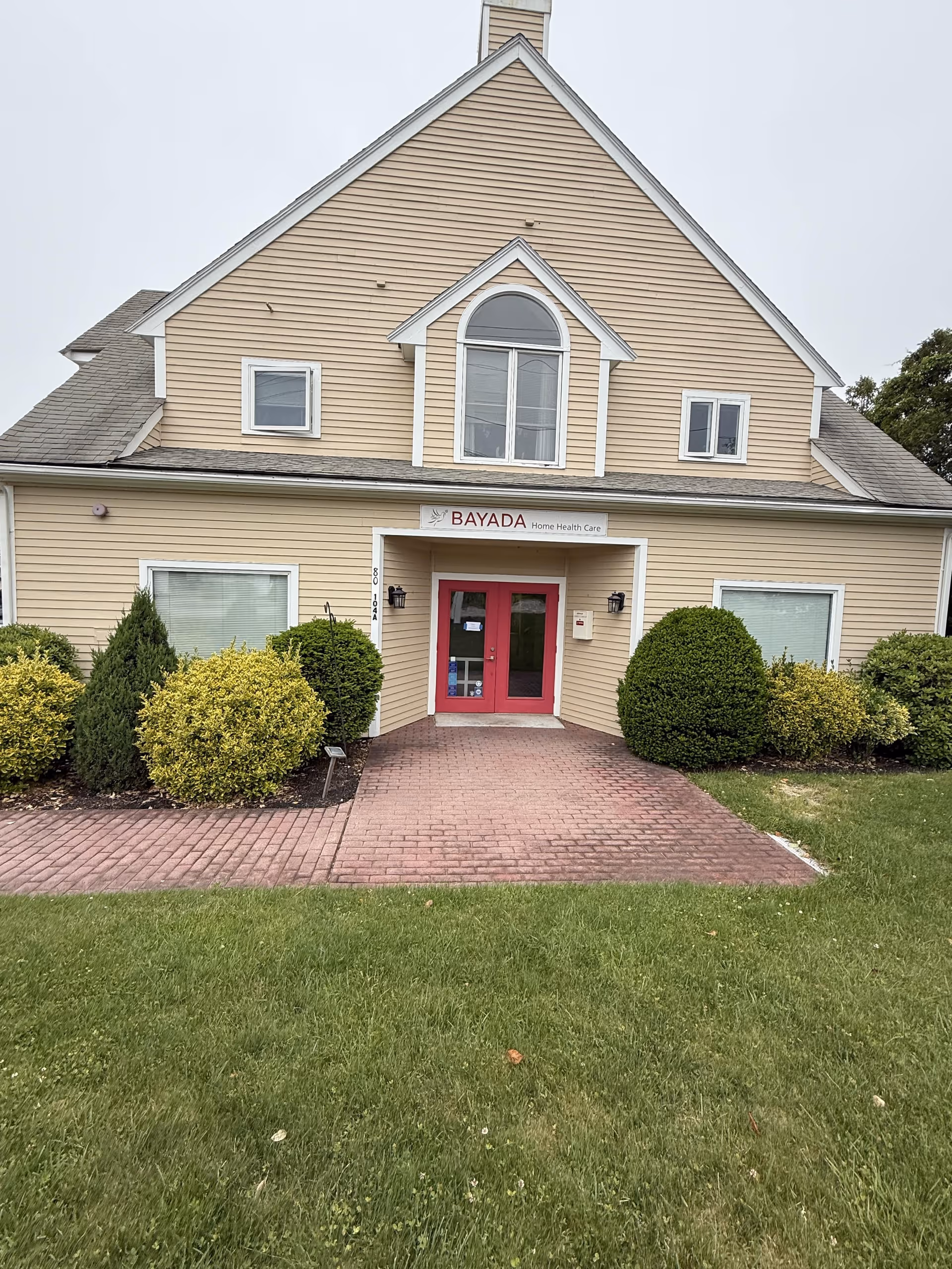 Exterior view of BAYADA facility entrance with brick walkway and landscaped shrubs.