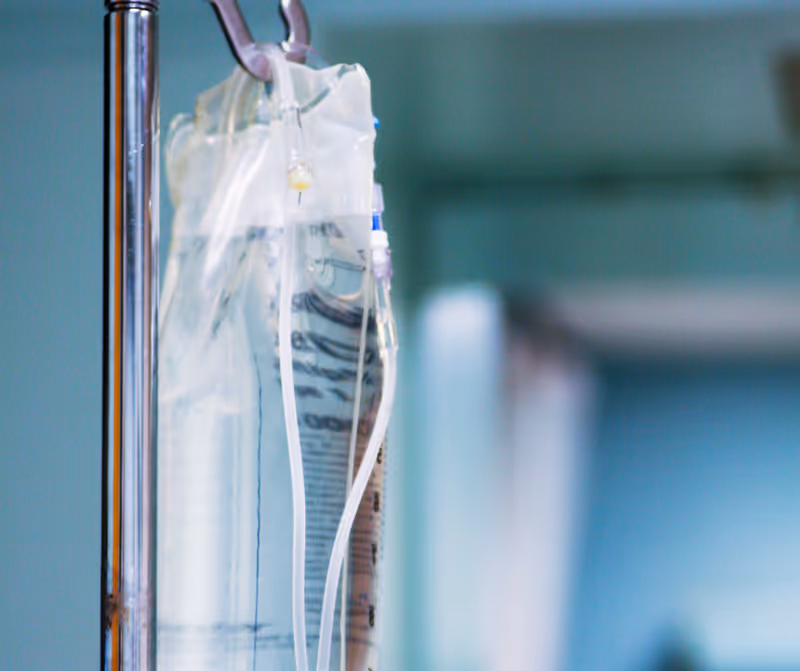 Close-up of an IV drip bag hung on a pole in a clinical interior.