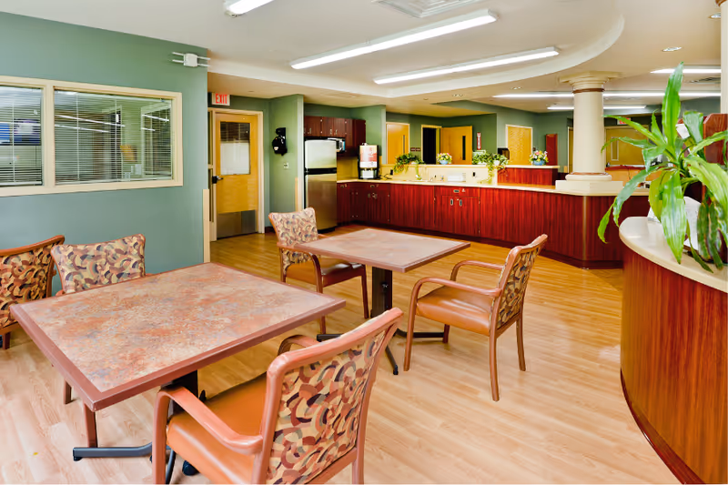 A spacious dining area with wooden tables, patterned chairs, and a long service counter.