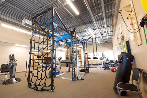 Indoor rehabilitation gym with climbing frames and therapy equipment.