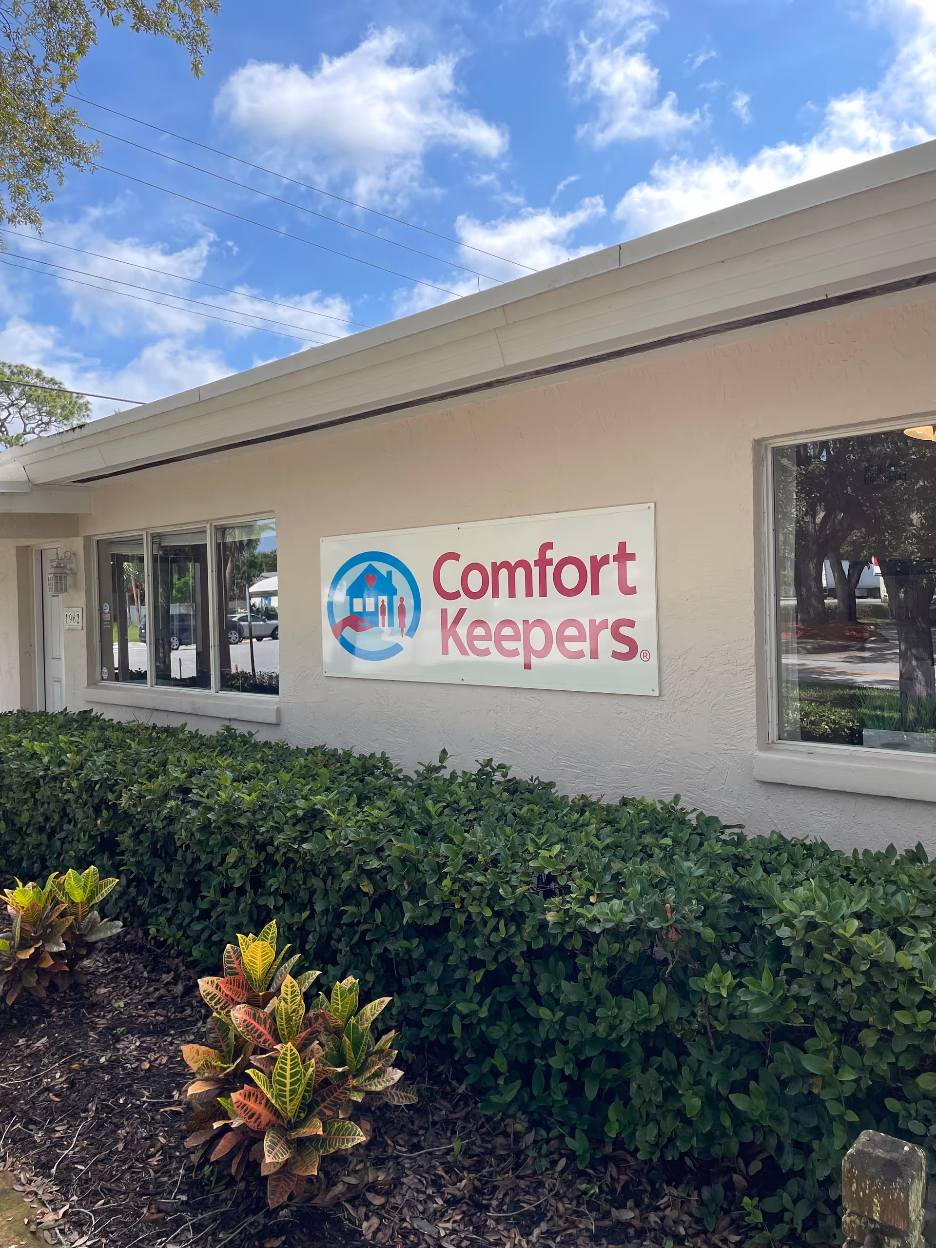 Exterior view of Comfort Keepers Home Care building with sign and landscaped shrubs.