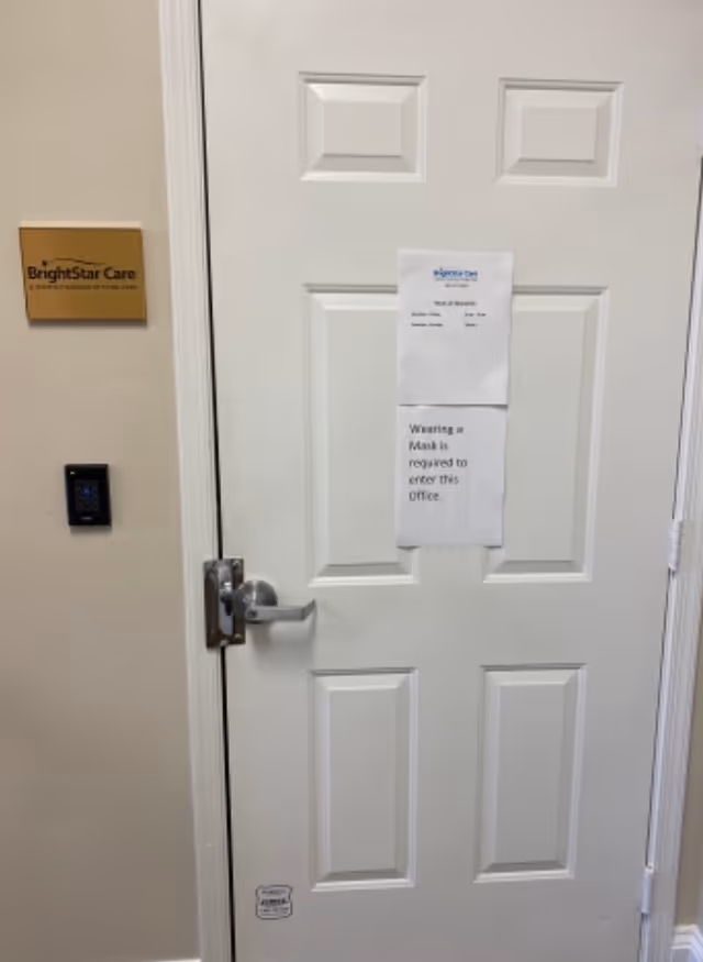Interior door with taped notice, BrightStar Care sign on wall, and keypad nearby.