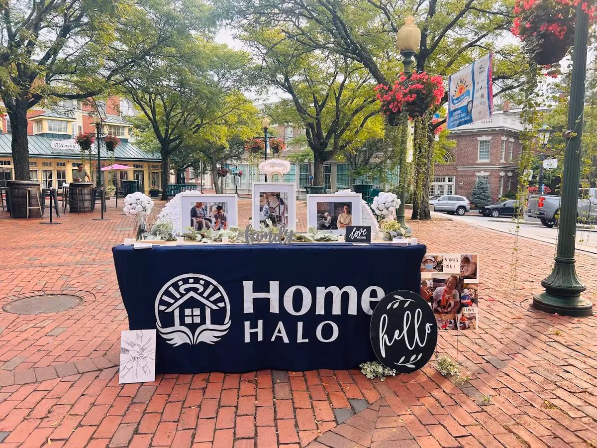 Outdoor display table with Home Halo branding in a brick plaza.