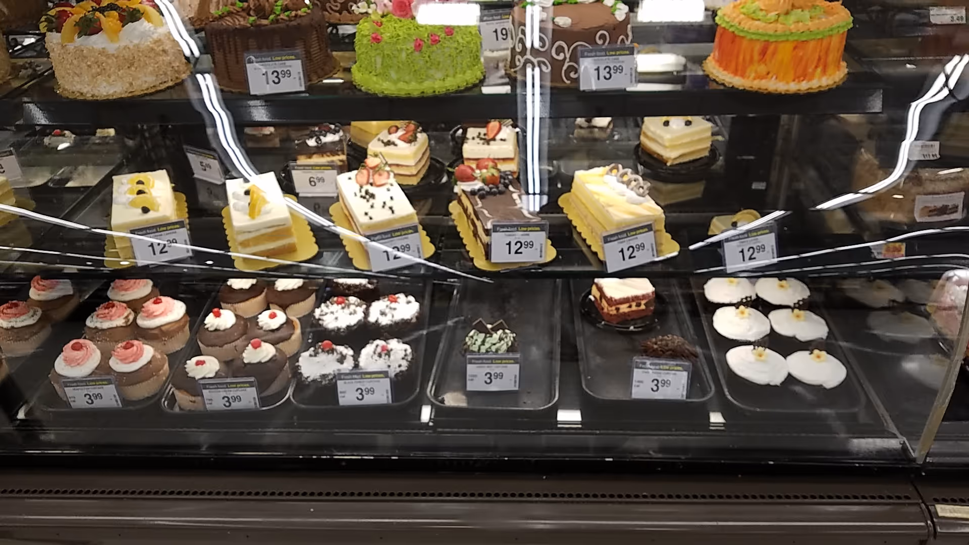 Glass bakery display case filled with assorted cakes and pastries.