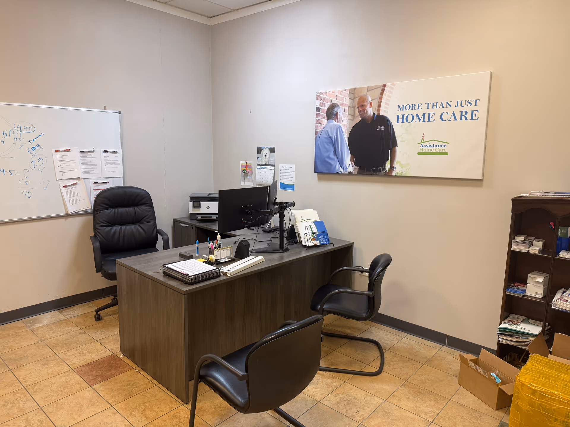 Office with desk, chairs, whiteboard, and a banner reading More Than Just Home Care.