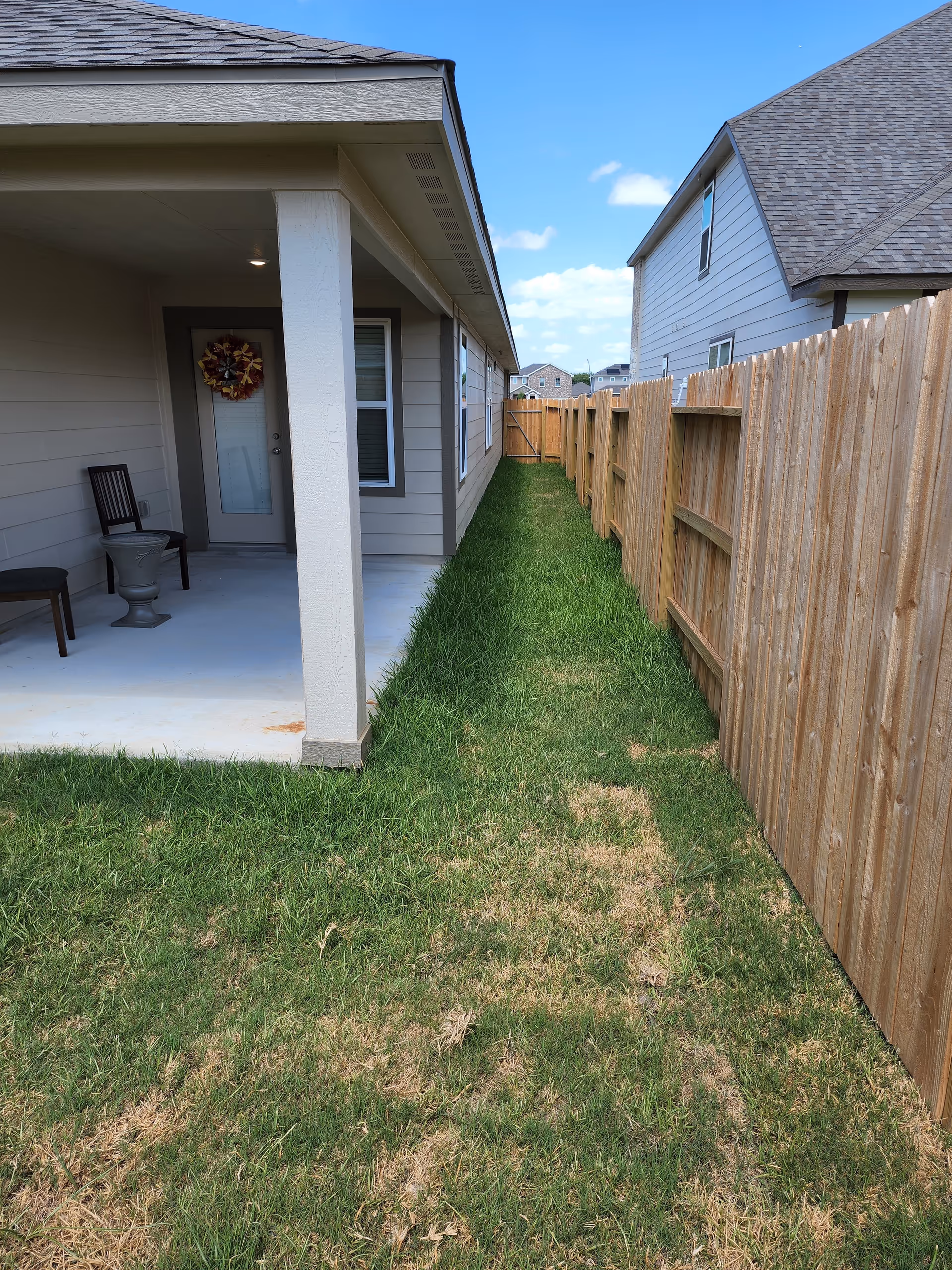 Outdoor view of a senior facility with a covered porch, seating, and wooden fence.